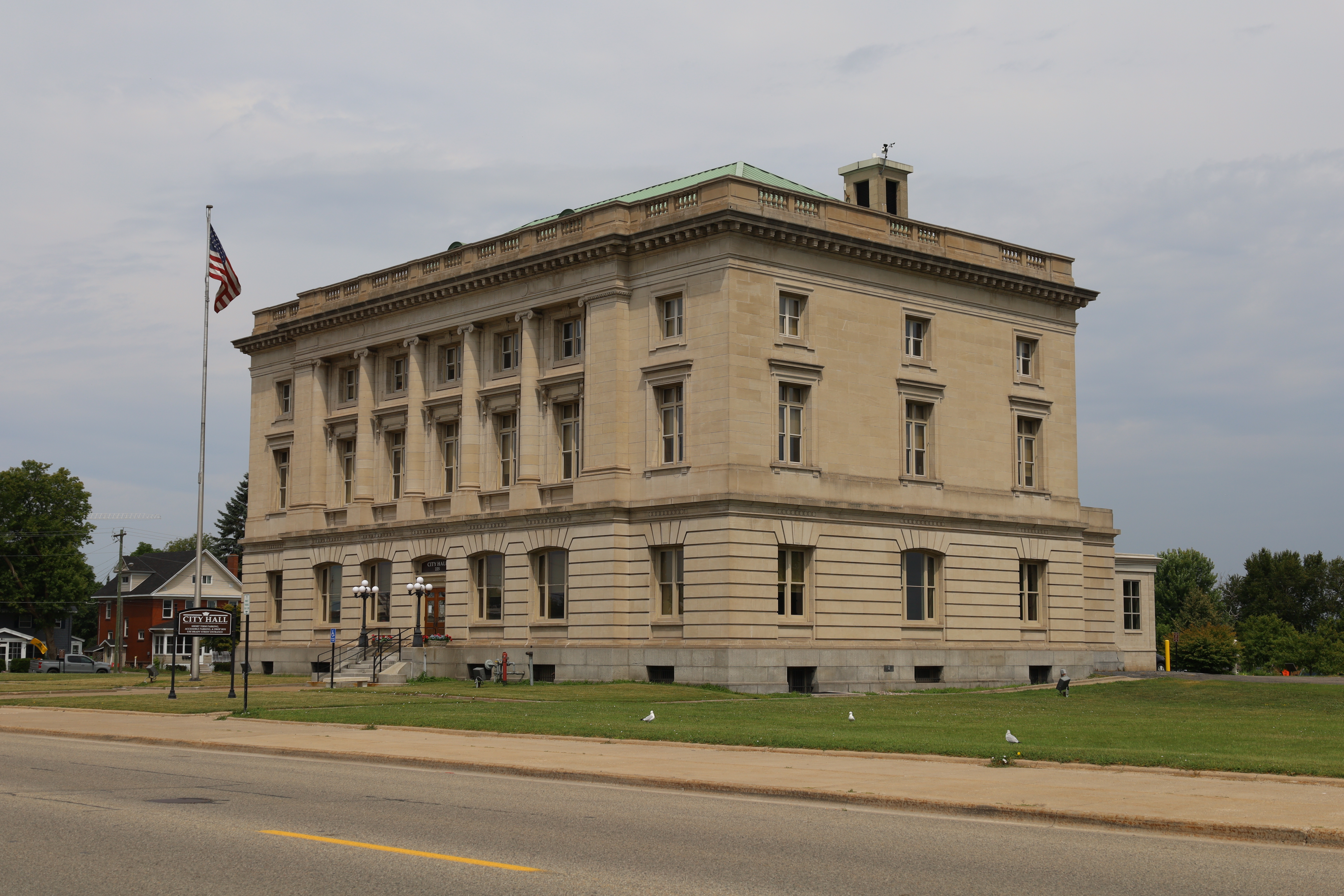 Neoclassical stone city hall building with American flag on a tall flagpole