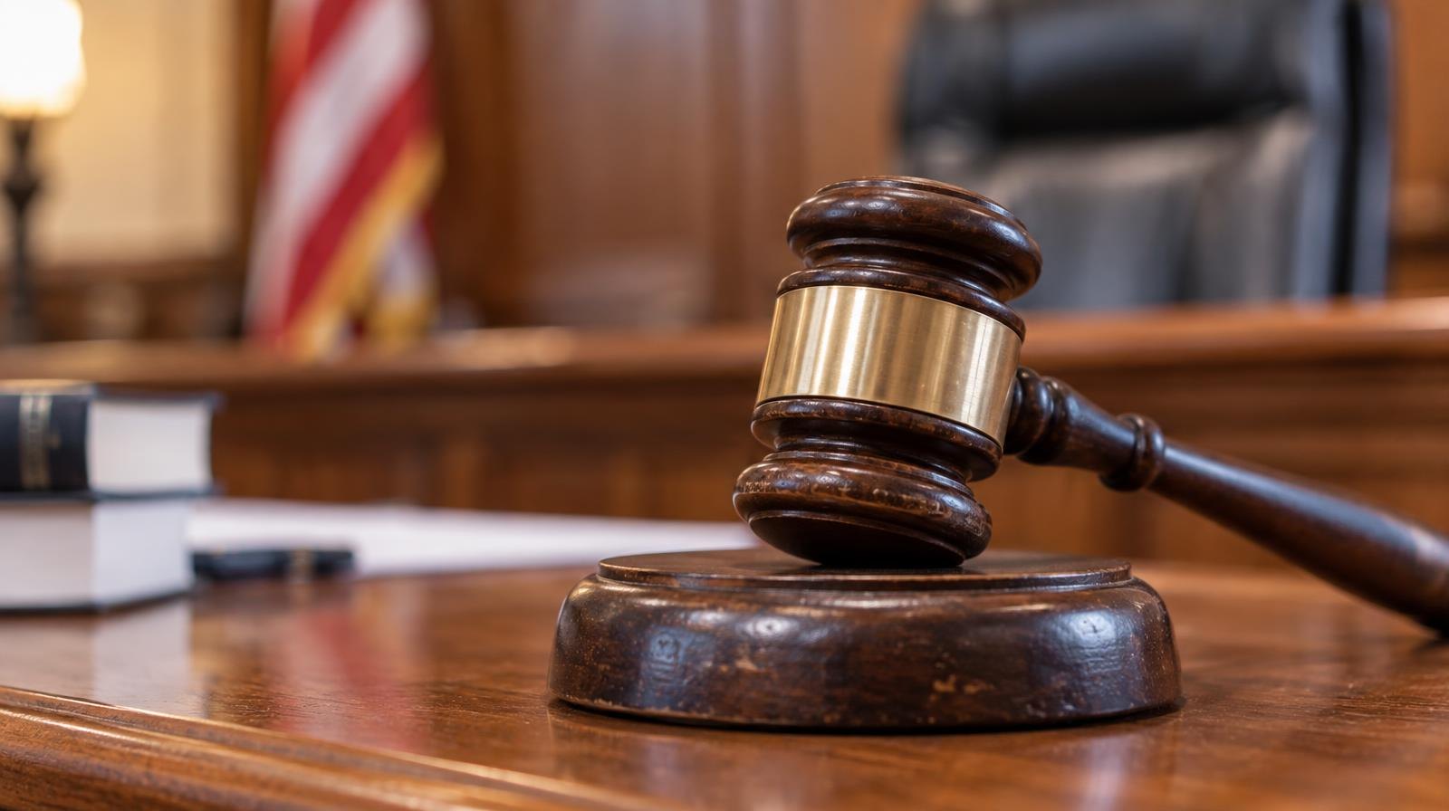 Wooden judge's gavel resting on its sound block on a wooden surface.