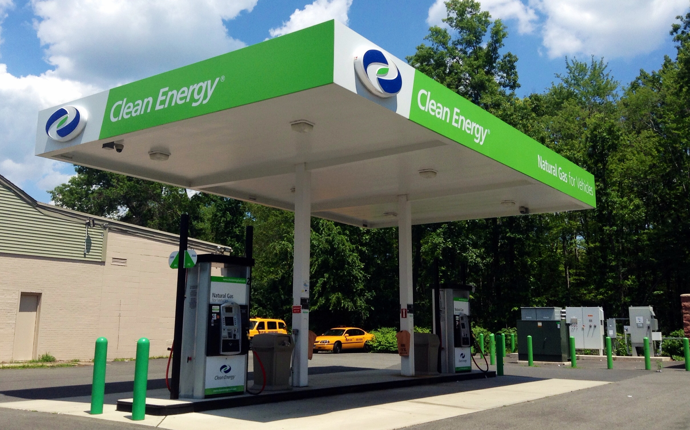 Green and white Clean Energy natural gas fueling station canopy with fuel dispensers