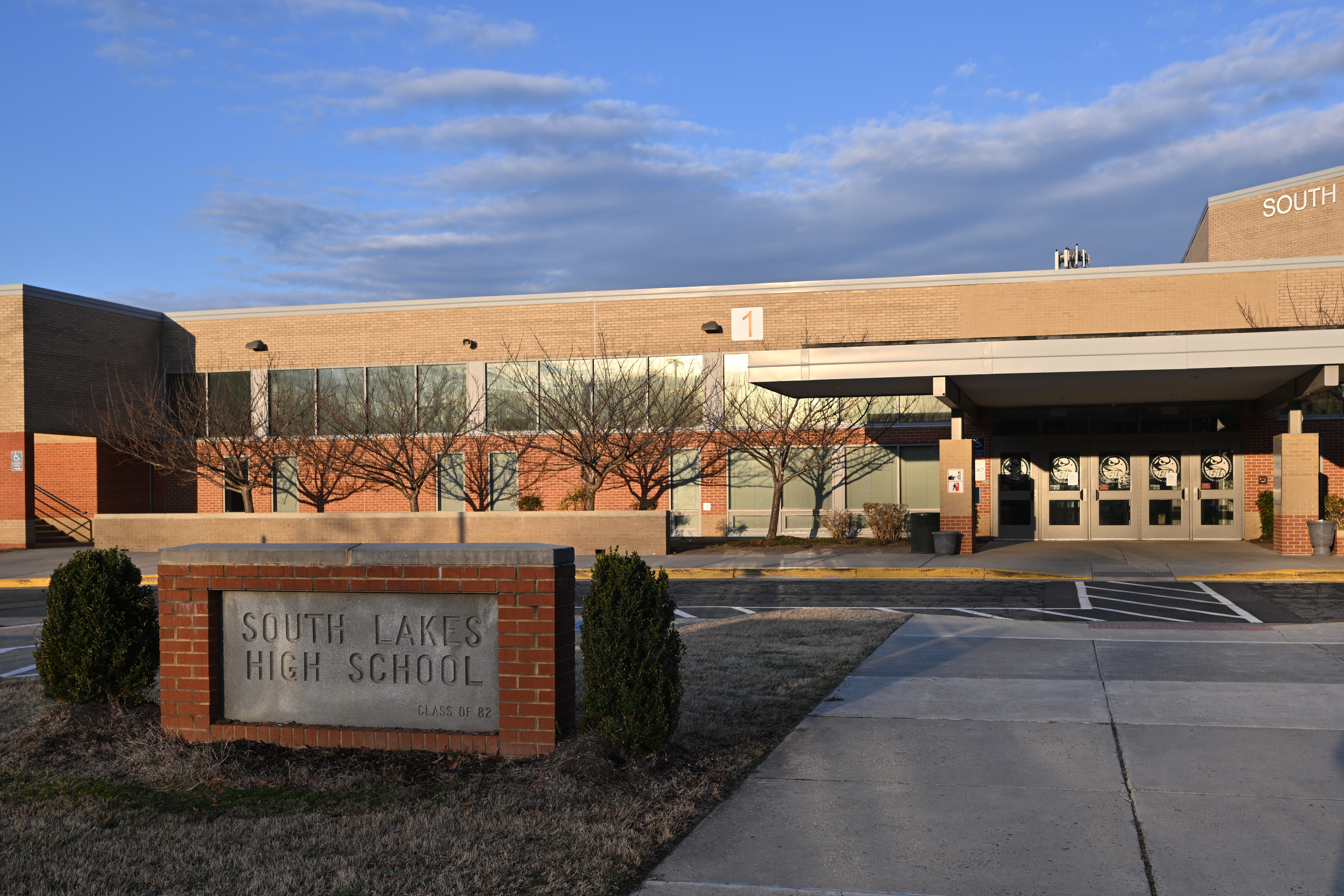 Brick sign reading South Lakes High School with the school building visible behind it.