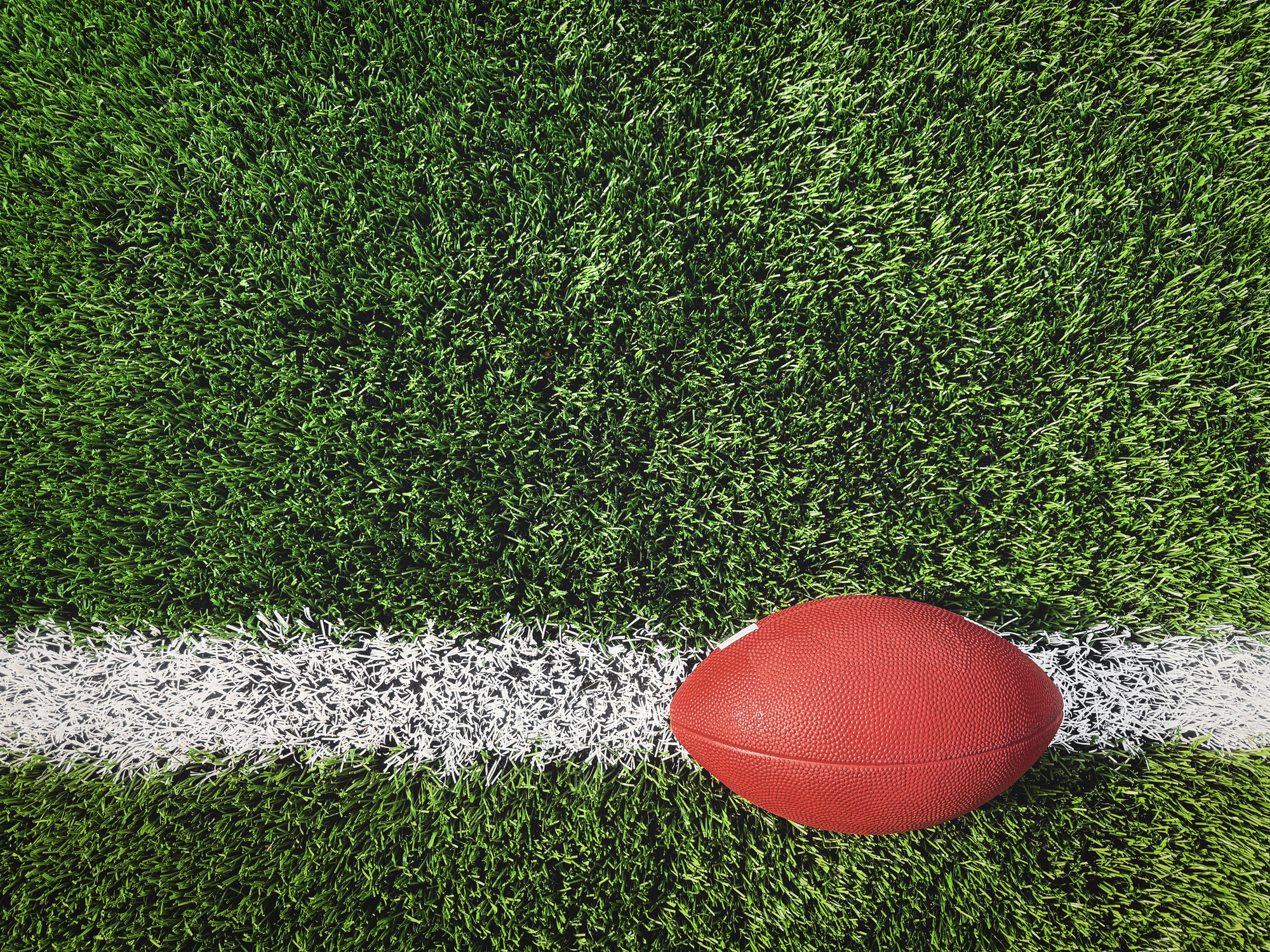 American Football on White Yard Line of Synthetic Turf Field