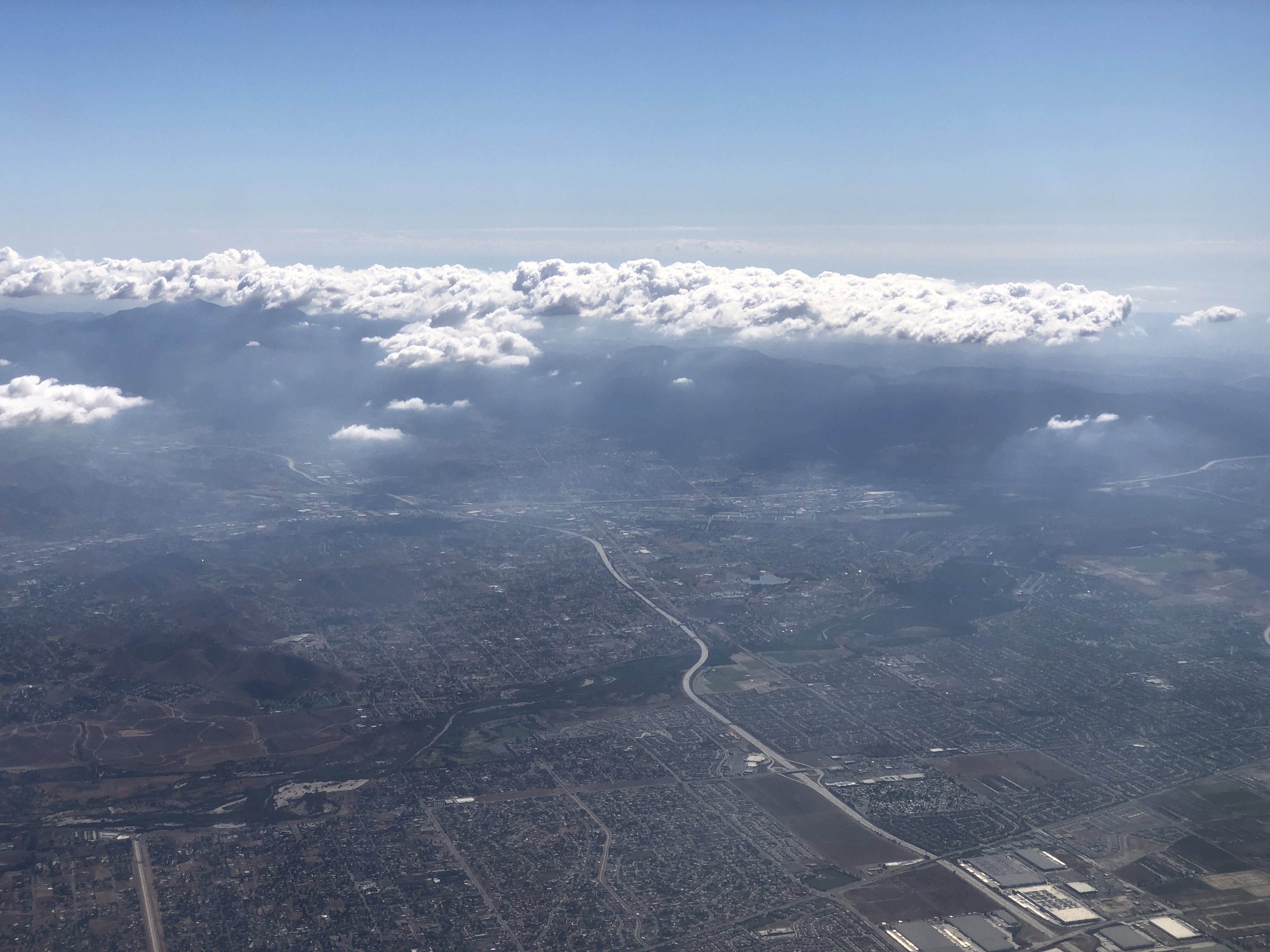 Aerial view of suburban sprawl in western Riverside County with a freeway corridor below.