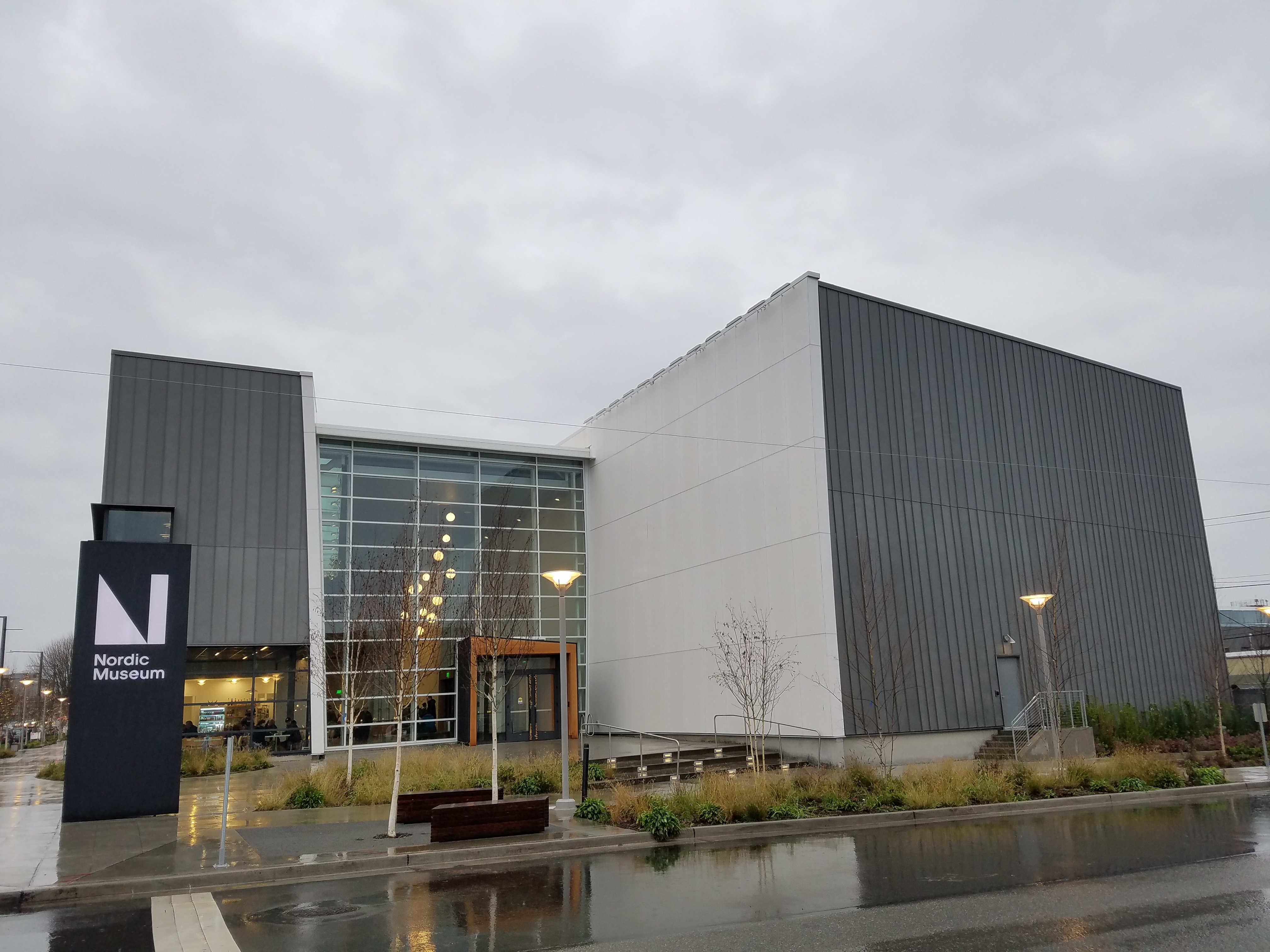 Exterior of the Nordic Museum building with a tall sign and modern gray cladding on an overcast day.