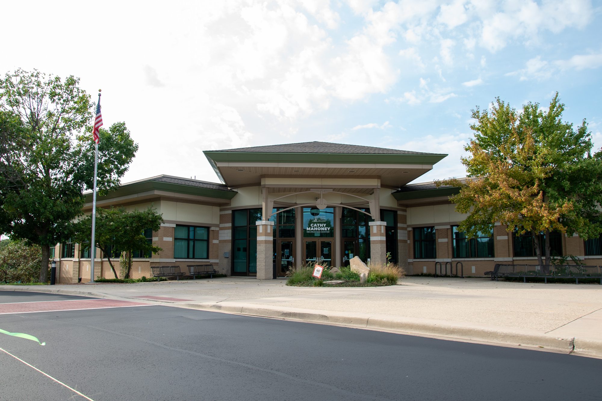 Single-story brick public building with covered entrance and American flag outside.