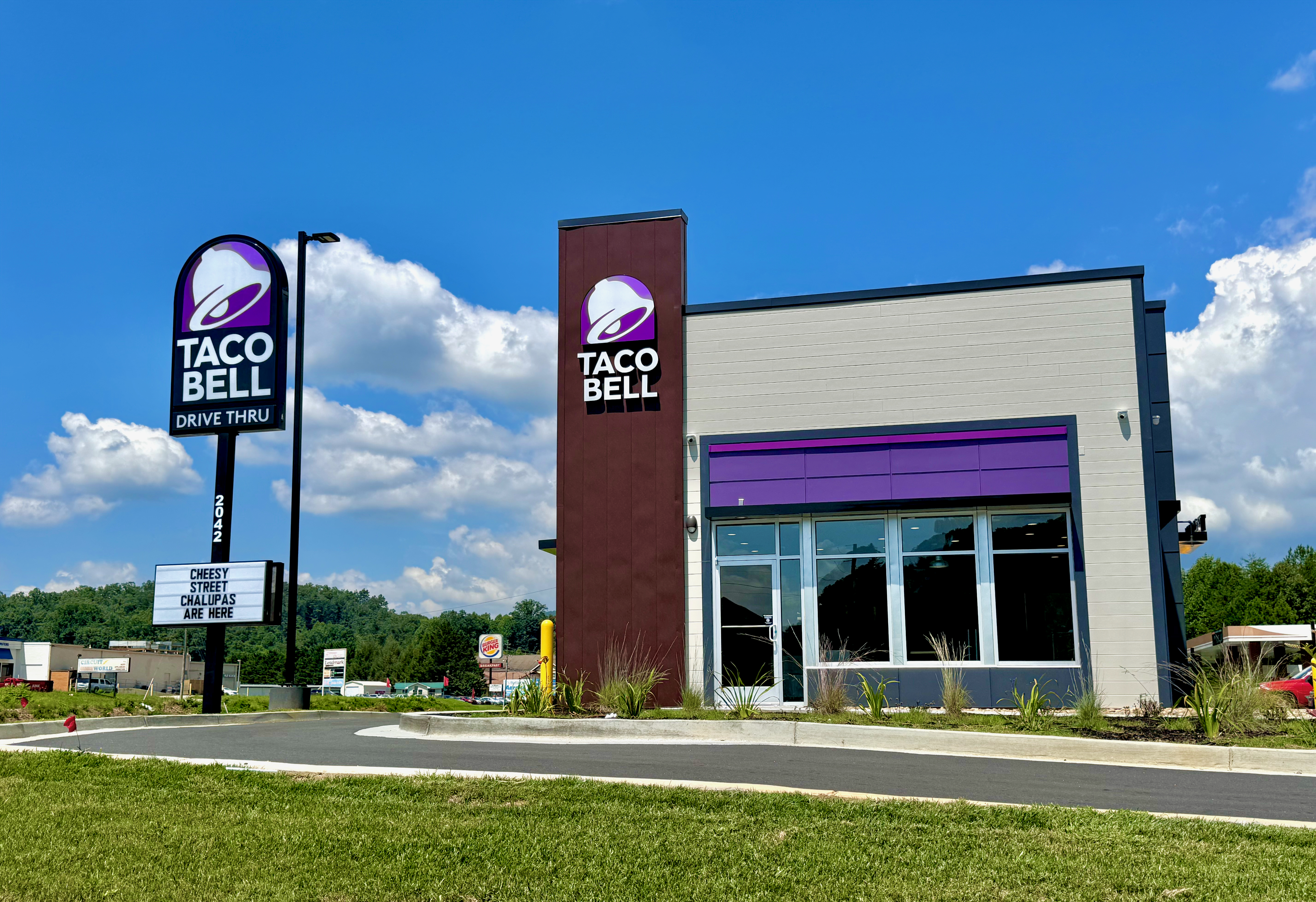 Exterior of a Taco Bell restaurant with purple accents and a drive-thru lane.