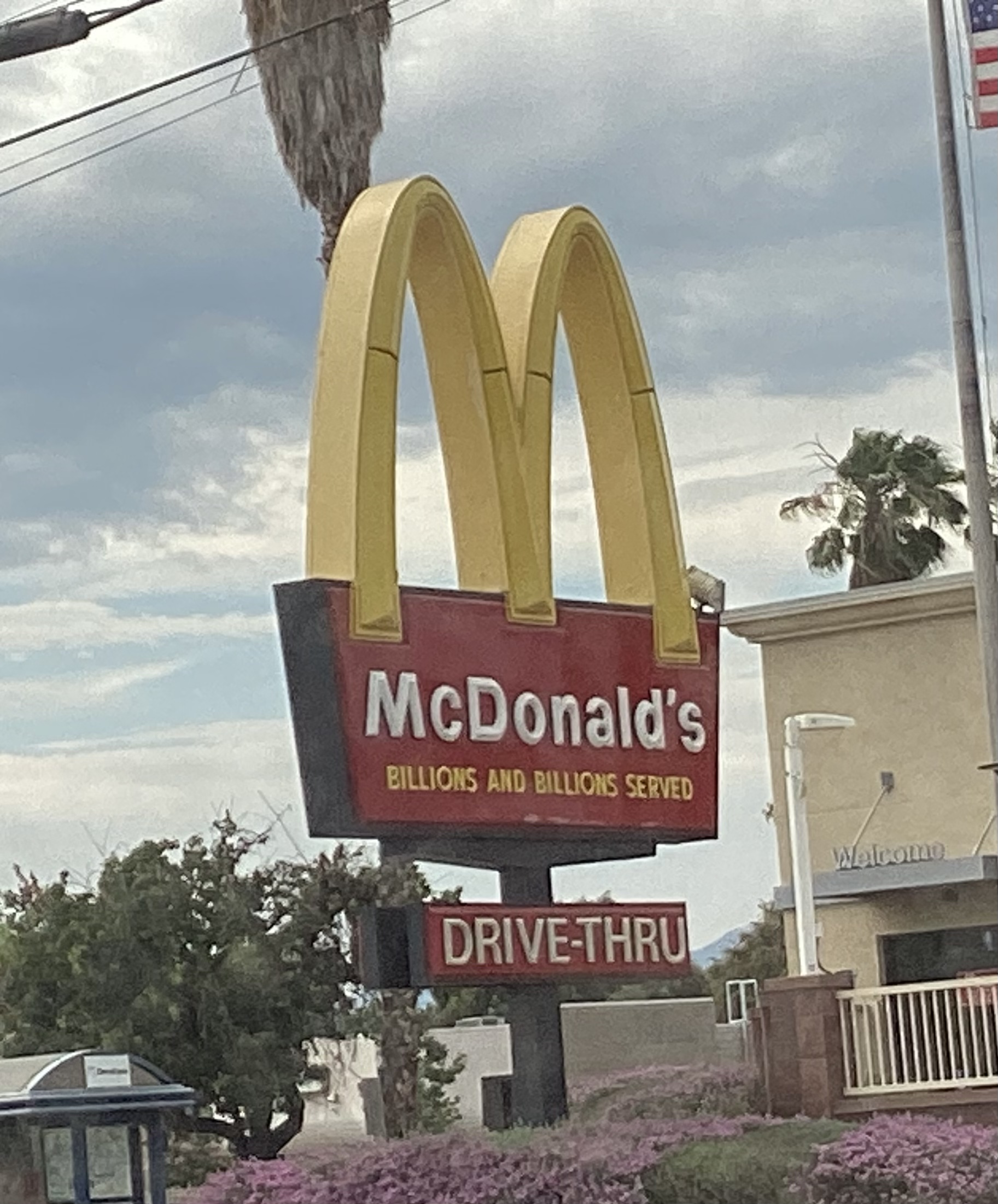 A tall McDonald's golden arches sign against a blue sky in California.