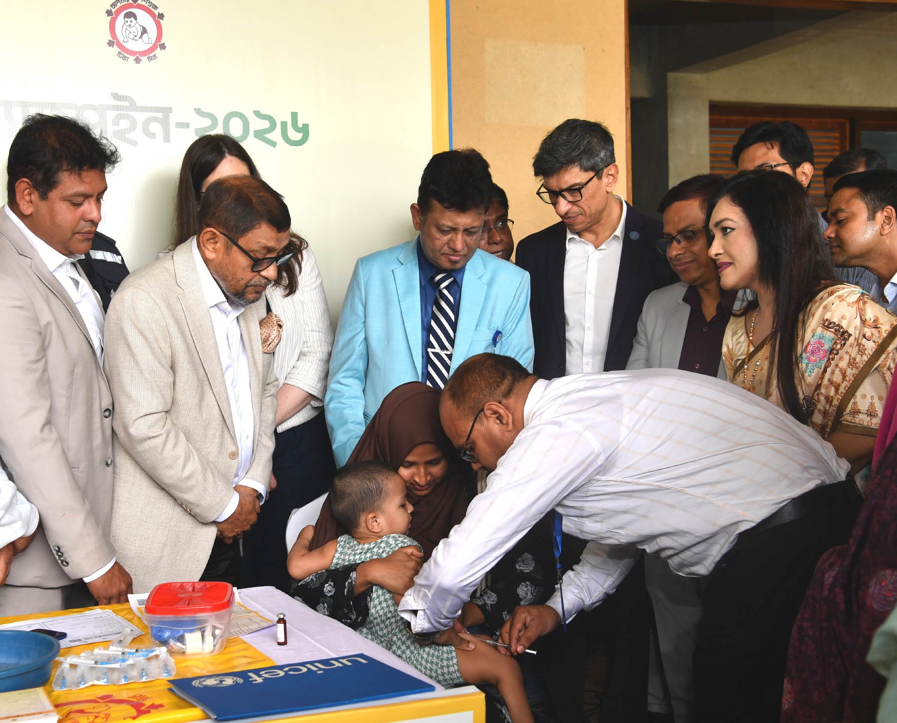Healthcare worker administers a vaccine to a young child held by a caregiver at a public event.
