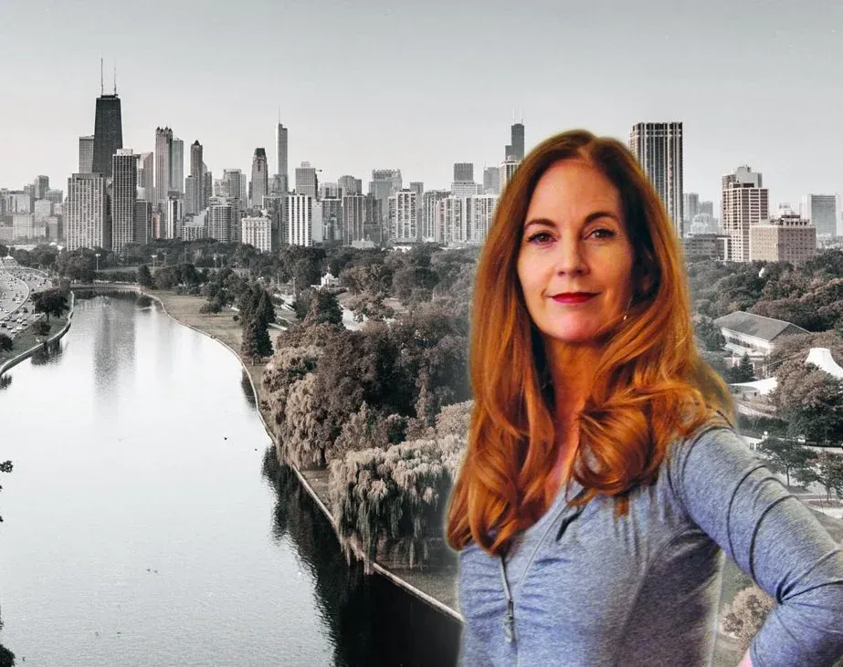 A woman with long auburn hair stands confidently in front of a black and white cityscape with a river and skyline, resembling Chicago, in the background.