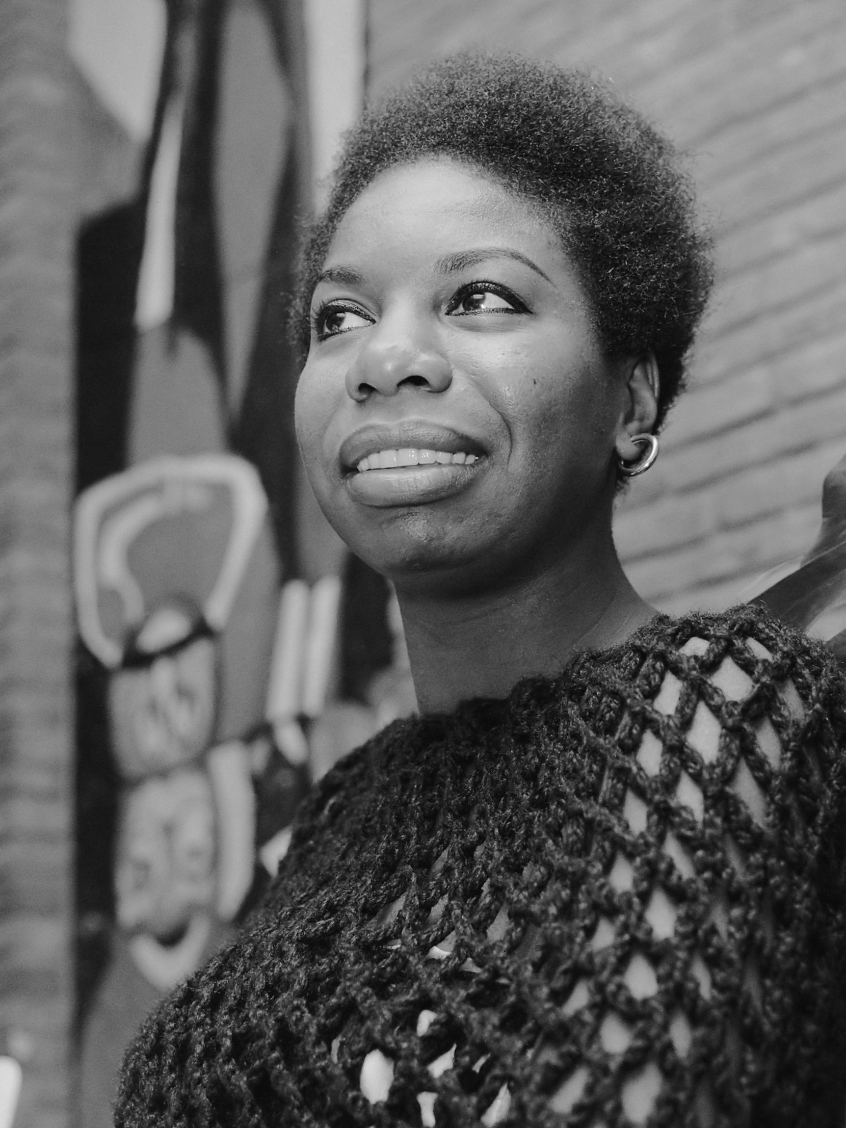 Black-and-white portrait of a young woman with a short natural hairstyle, smiling and looking upward.