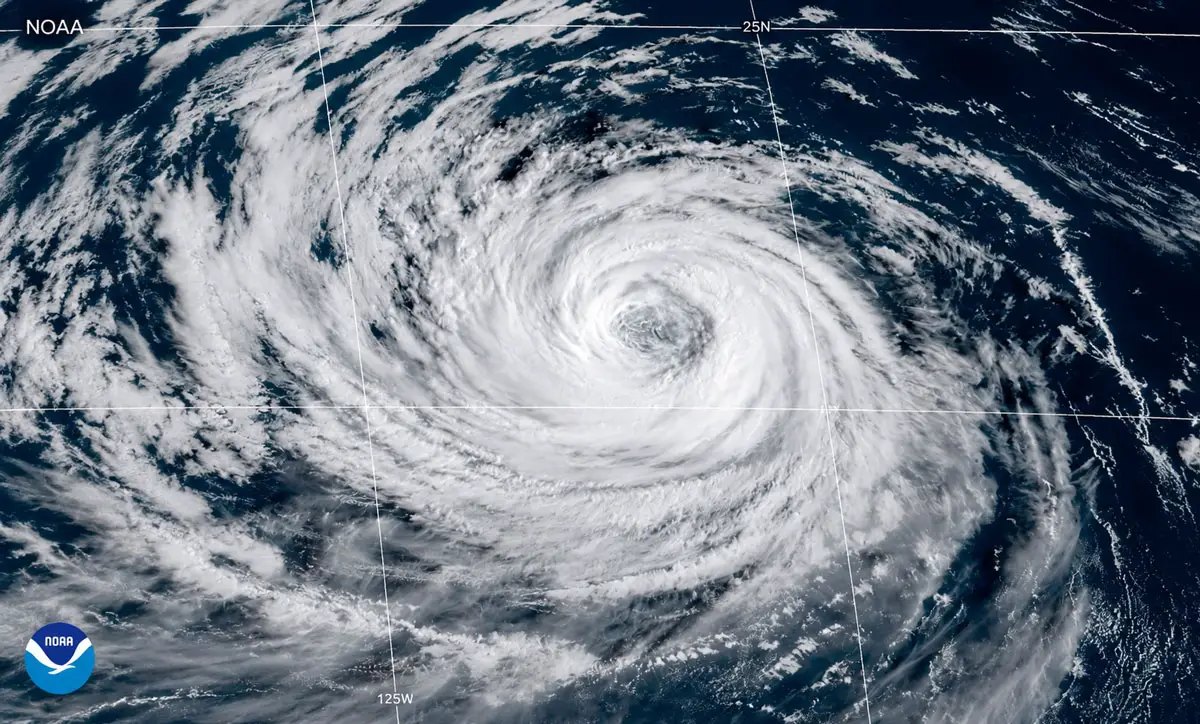 Satellite view of a tropical cyclone with a defined eye and spiral cloud bands over open ocean.