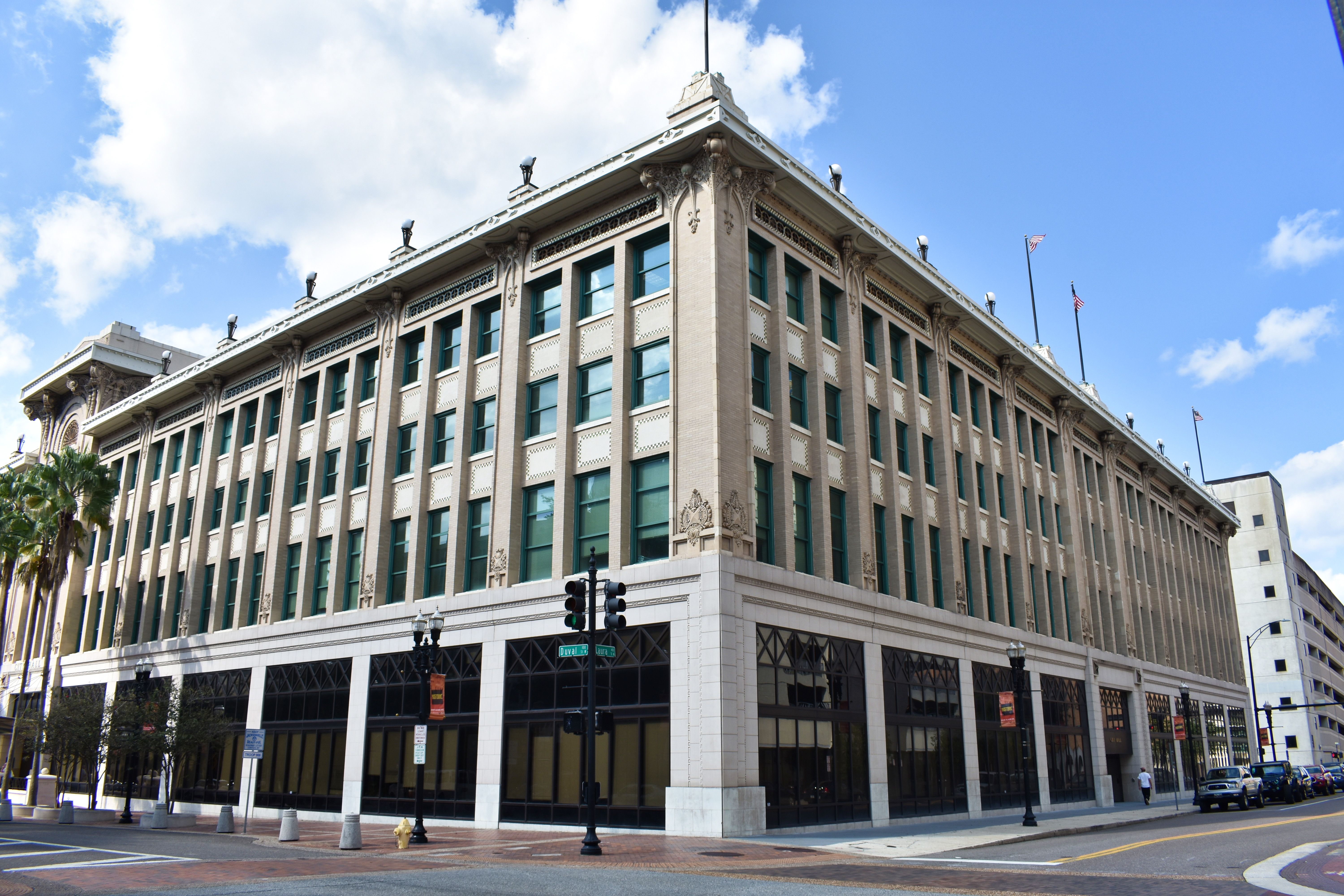 Corner view of Jacksonville City Hall, a multi-story Beaux-Arts building with palm trees.