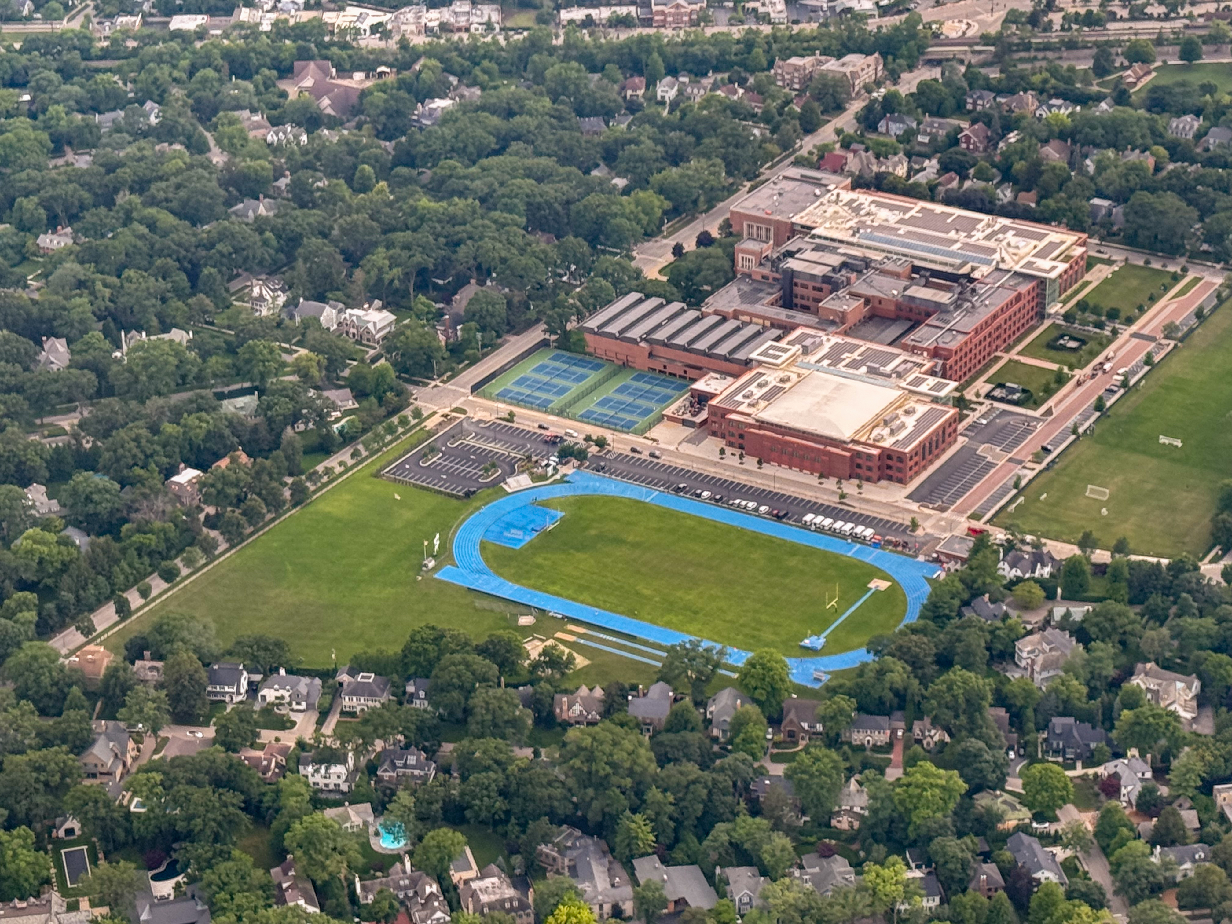 Aerial view of a large brick high school campus with a blue running track and athletic fields.