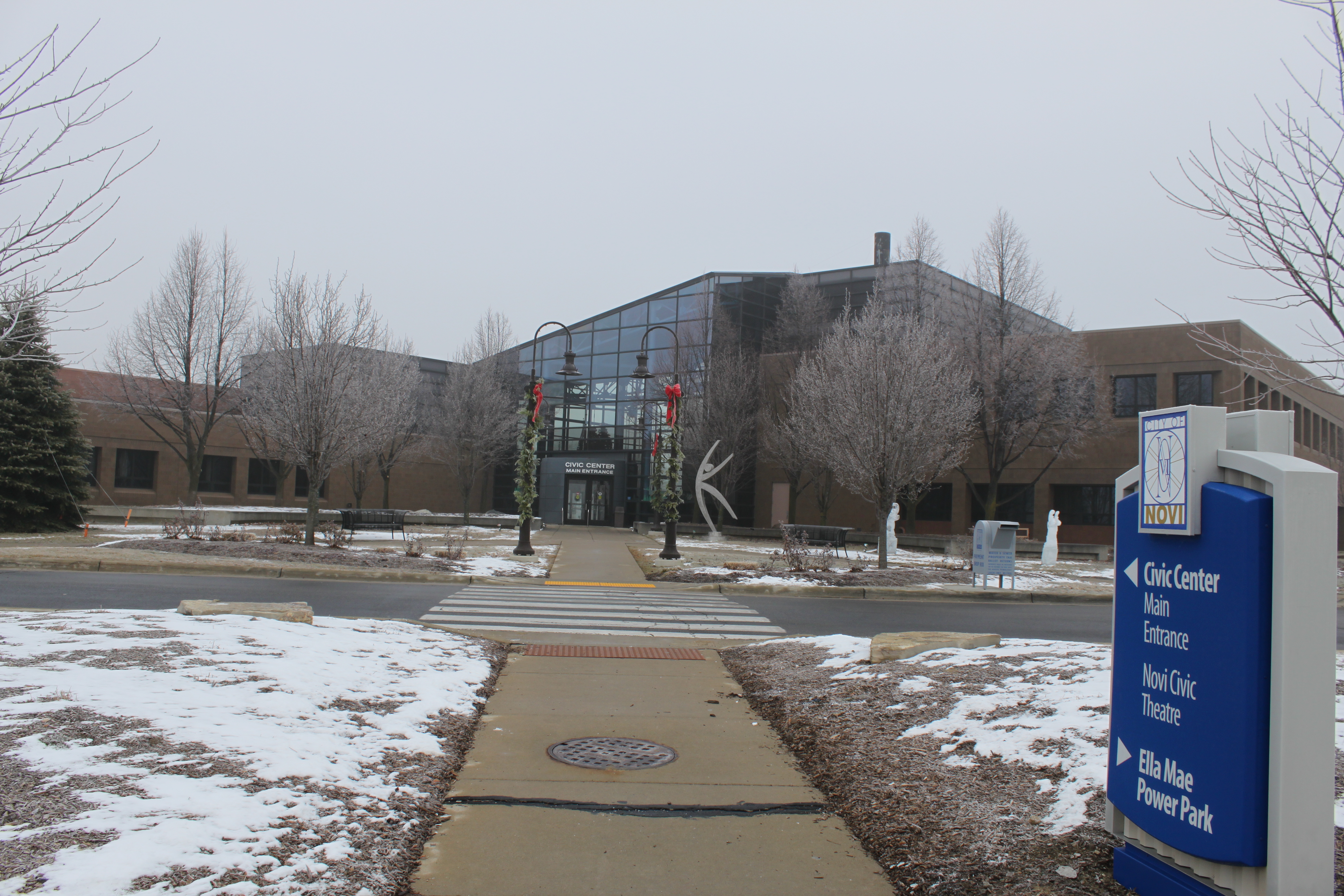 Large municipal civic center building with glass entrance and light snow on the ground.