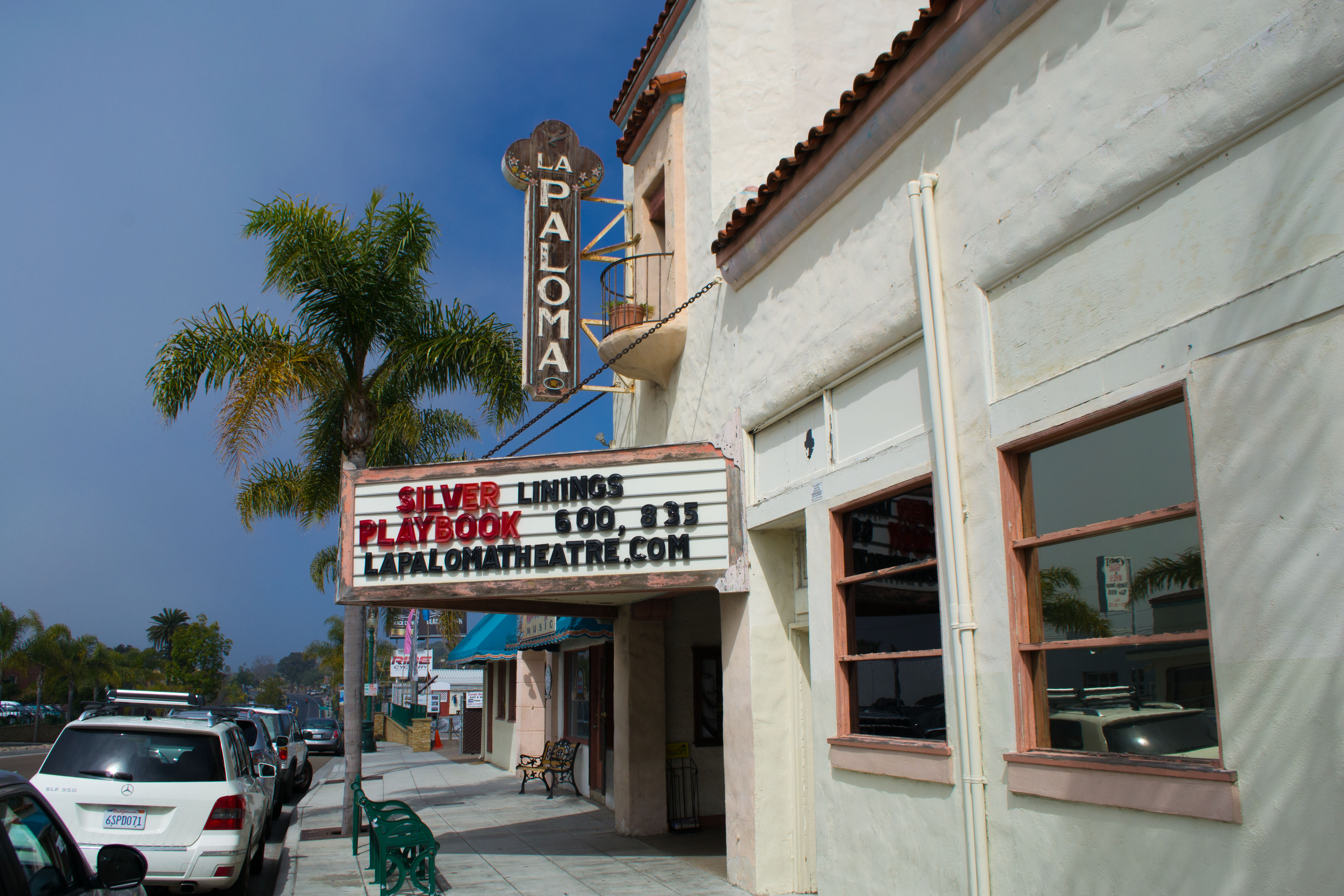 Exterior of La Paloma Theatre with vertical neon sign, marquee, and palm tree