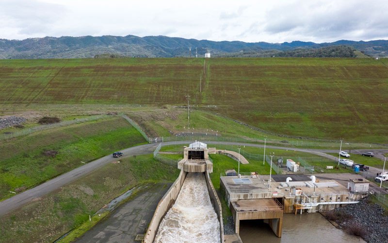 Aerial view of a concrete dam spillway with water flowing through a channel.