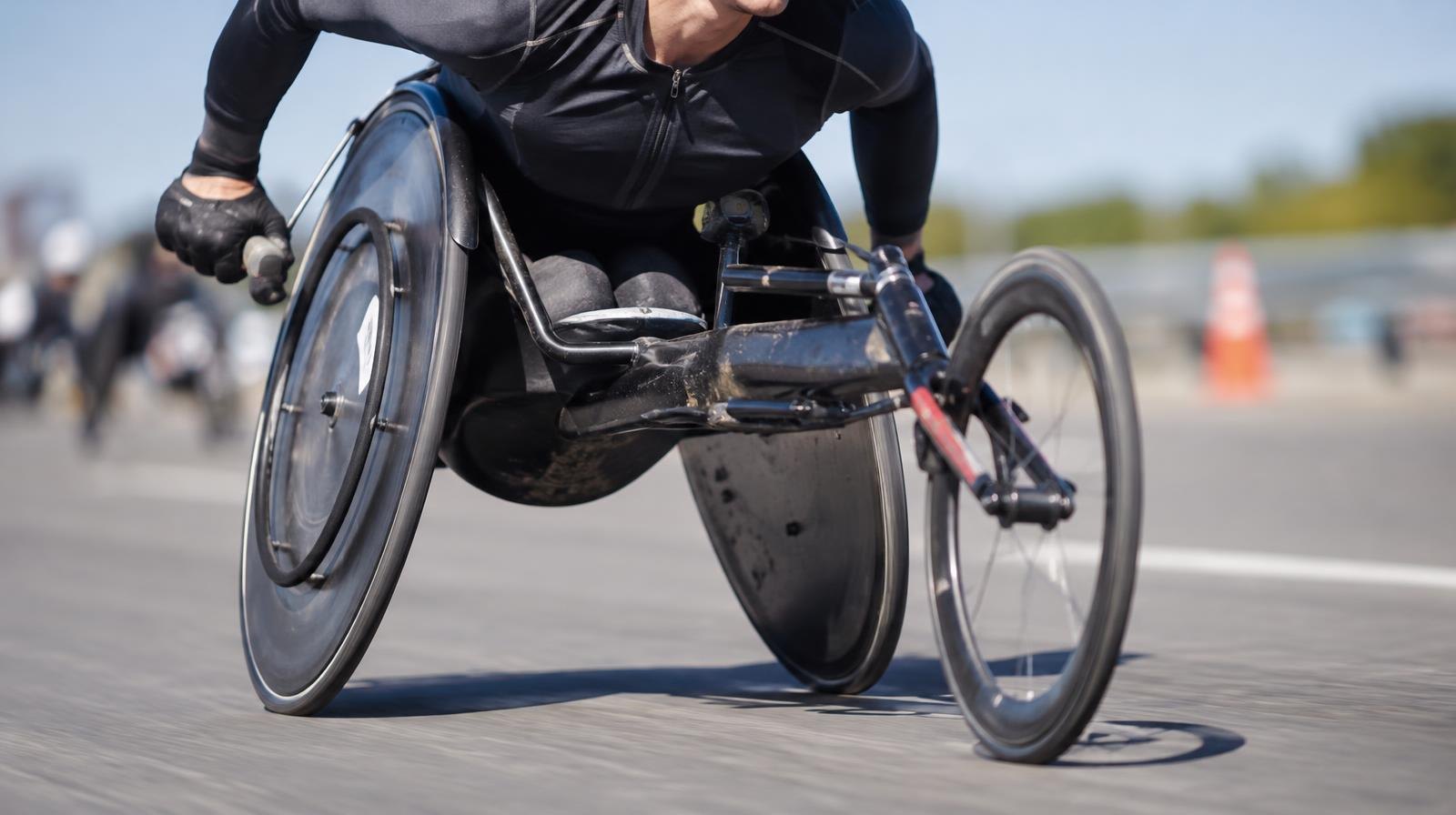 A hand-cycle racing wheelchair on a smooth road with motion blur.