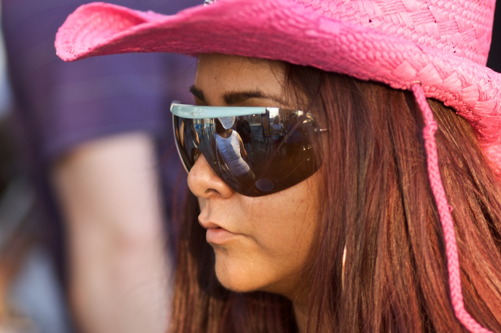Woman in a pink cowboy hat and large mirrored sunglasses, photographed in close-up profile.
