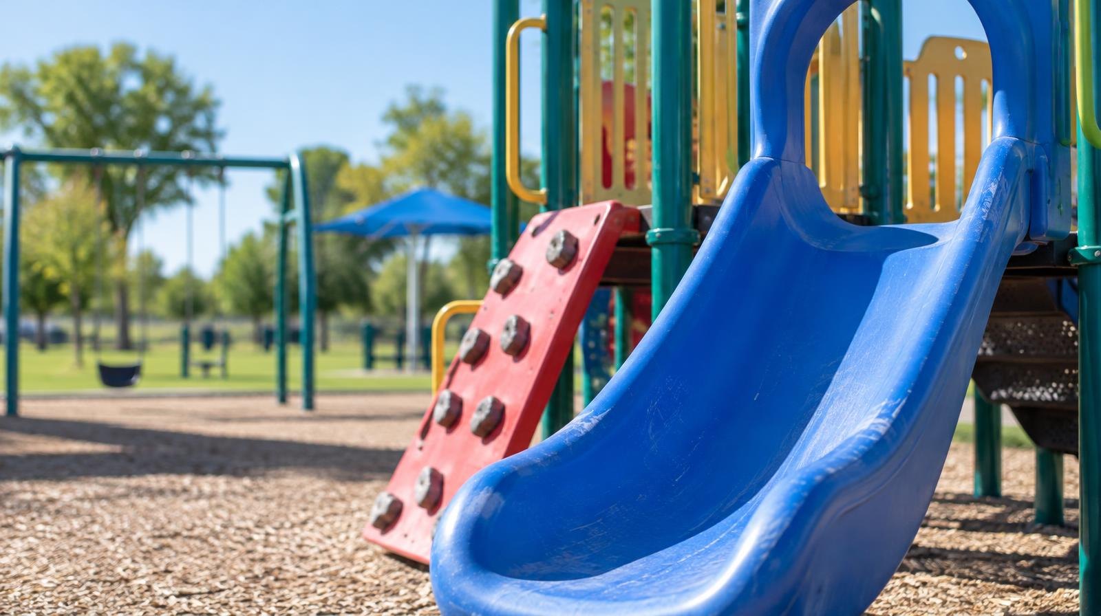 Colorful playground equipment with slides and climbing structures in a sunny park.