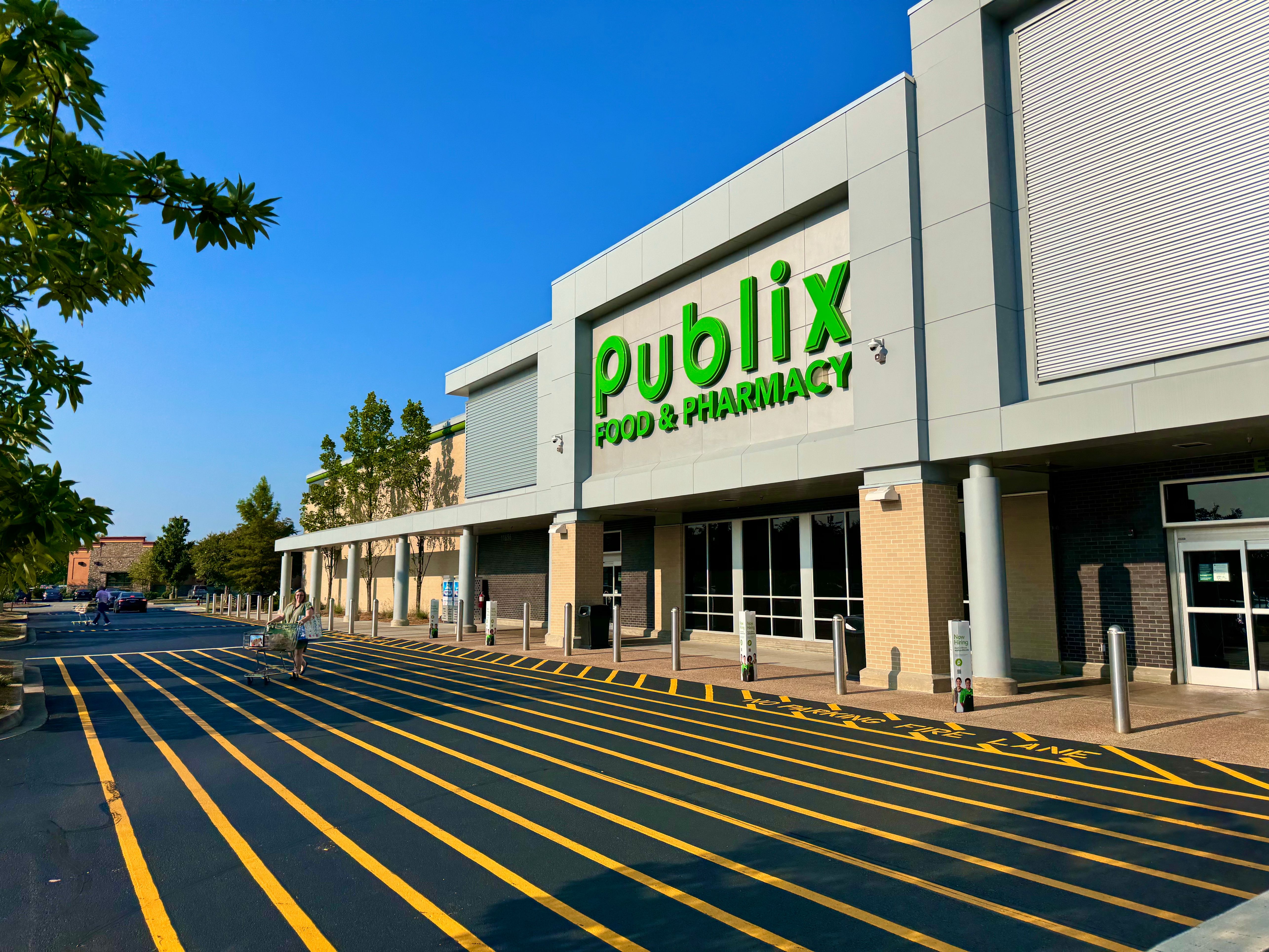 Publix Food and Pharmacy store exterior with green sign and striped parking lot under blue sky.