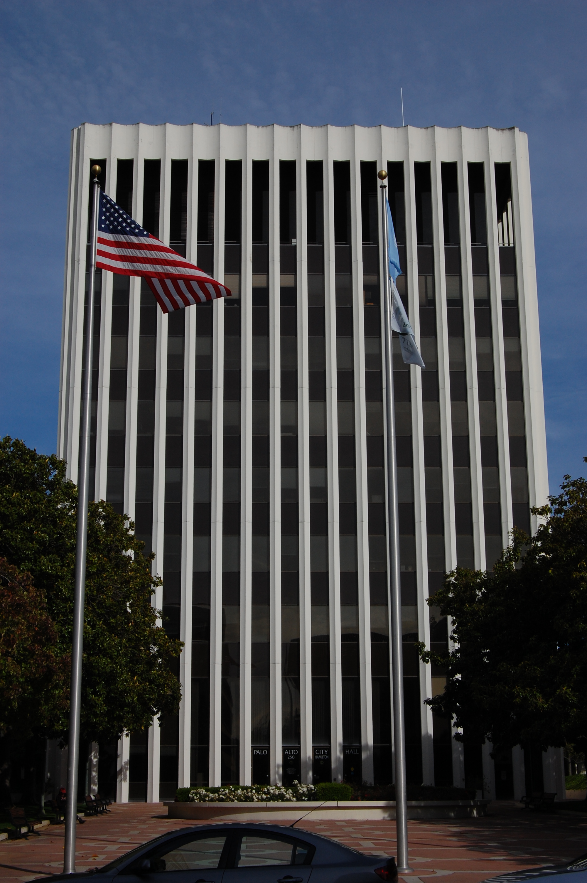 Tall modernist building with vertical white fins and two flags out front.