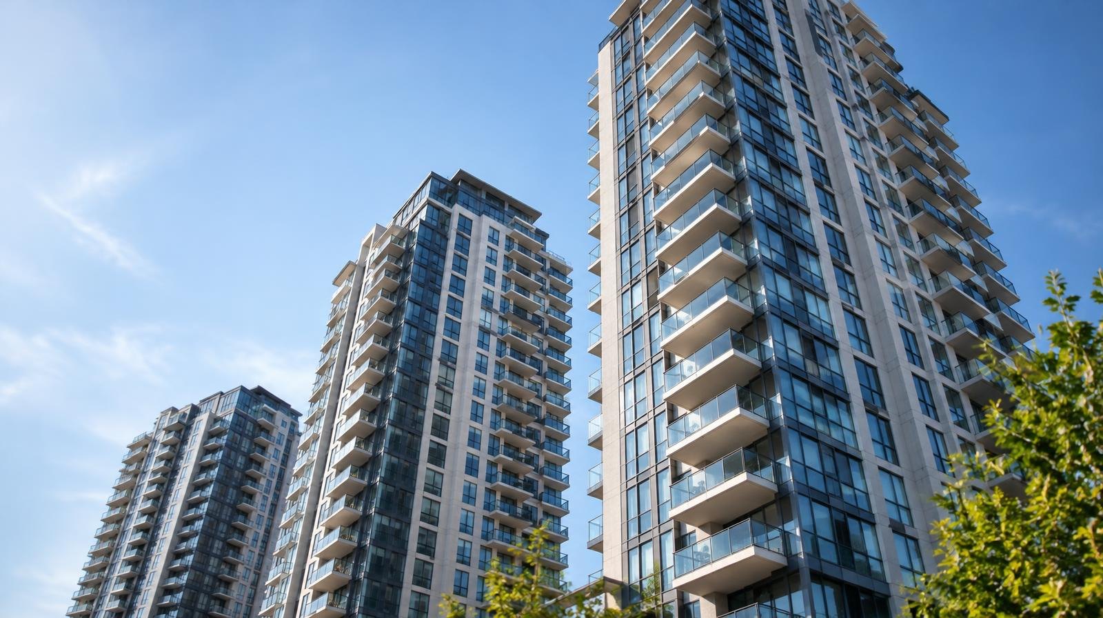 Three modern high-rise residential towers viewed from street level against a blue sky.