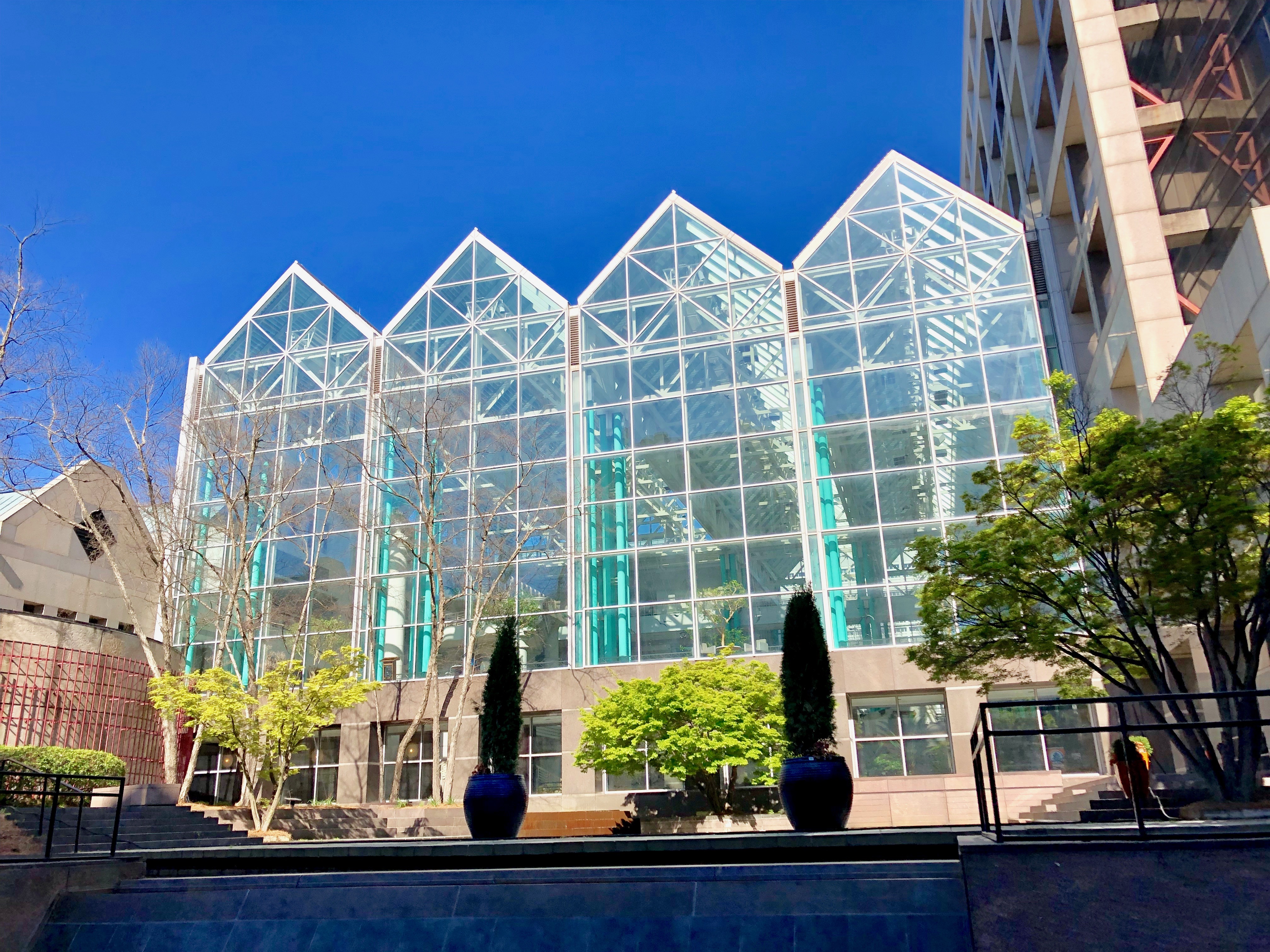 Modern glass atrium government building with peaked steel rooflines and landscaped courtyard.