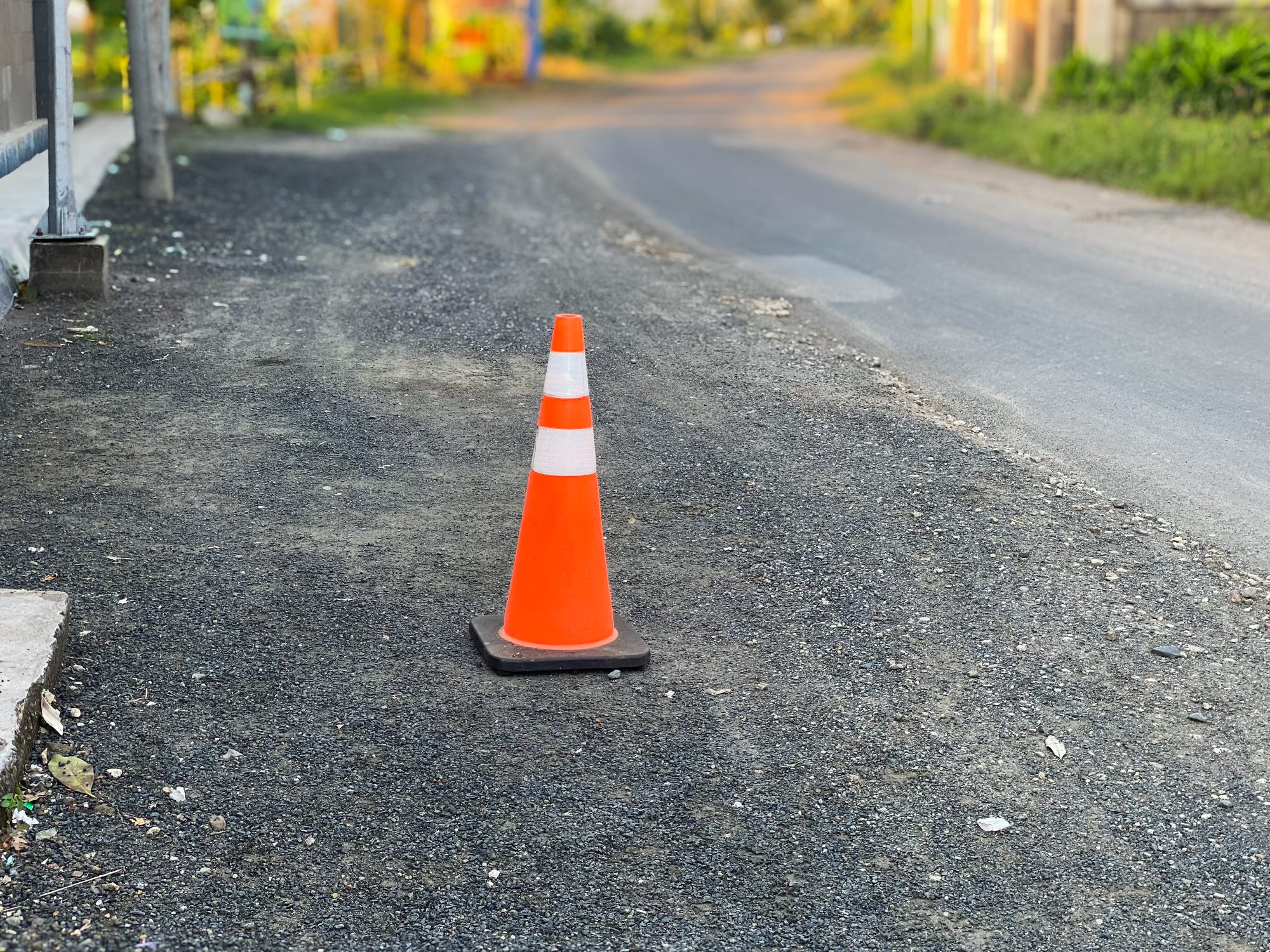 Triangular traffic cone on the side of the damaged road.