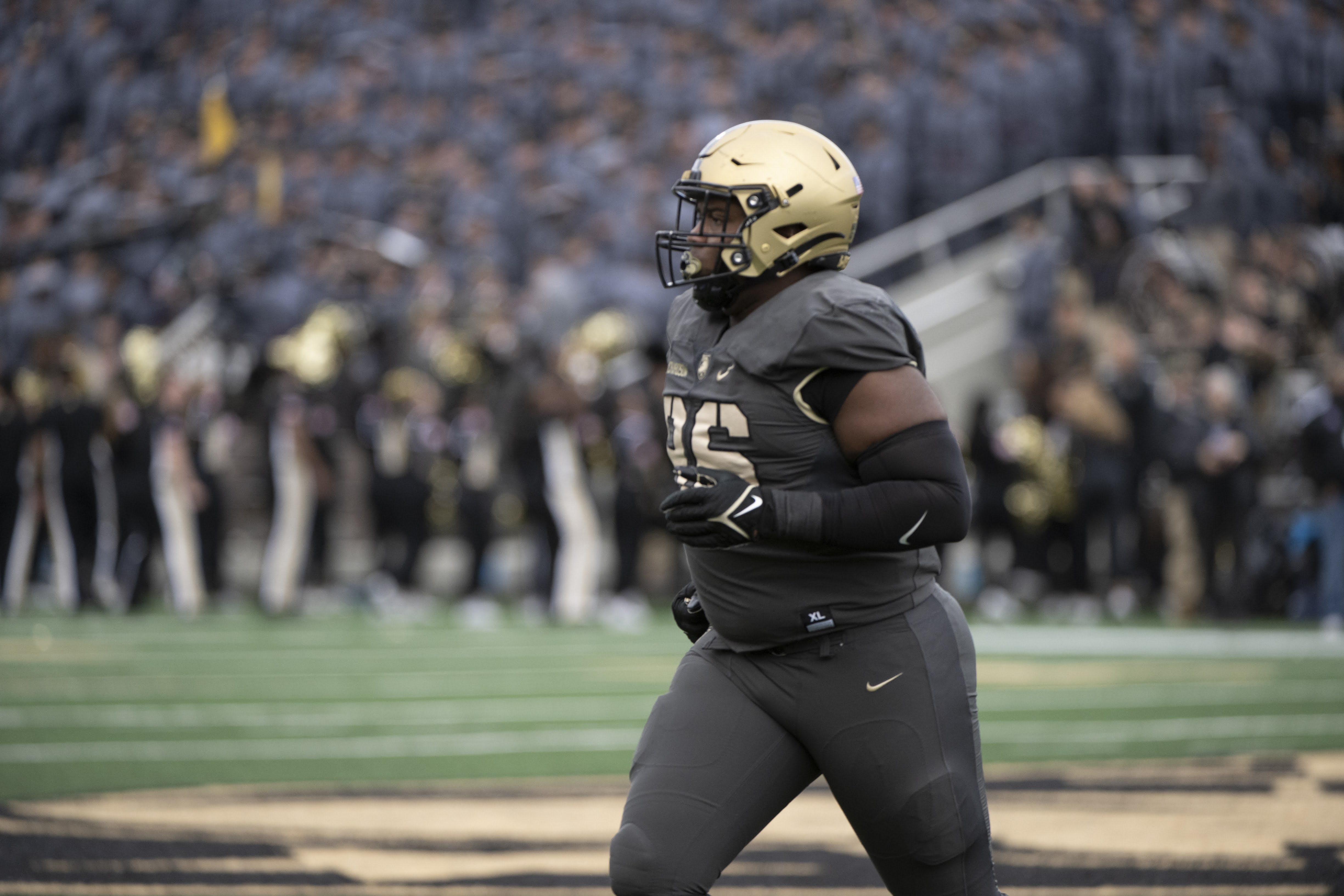 Army football player in dark gray uniform and black helmet on the field.