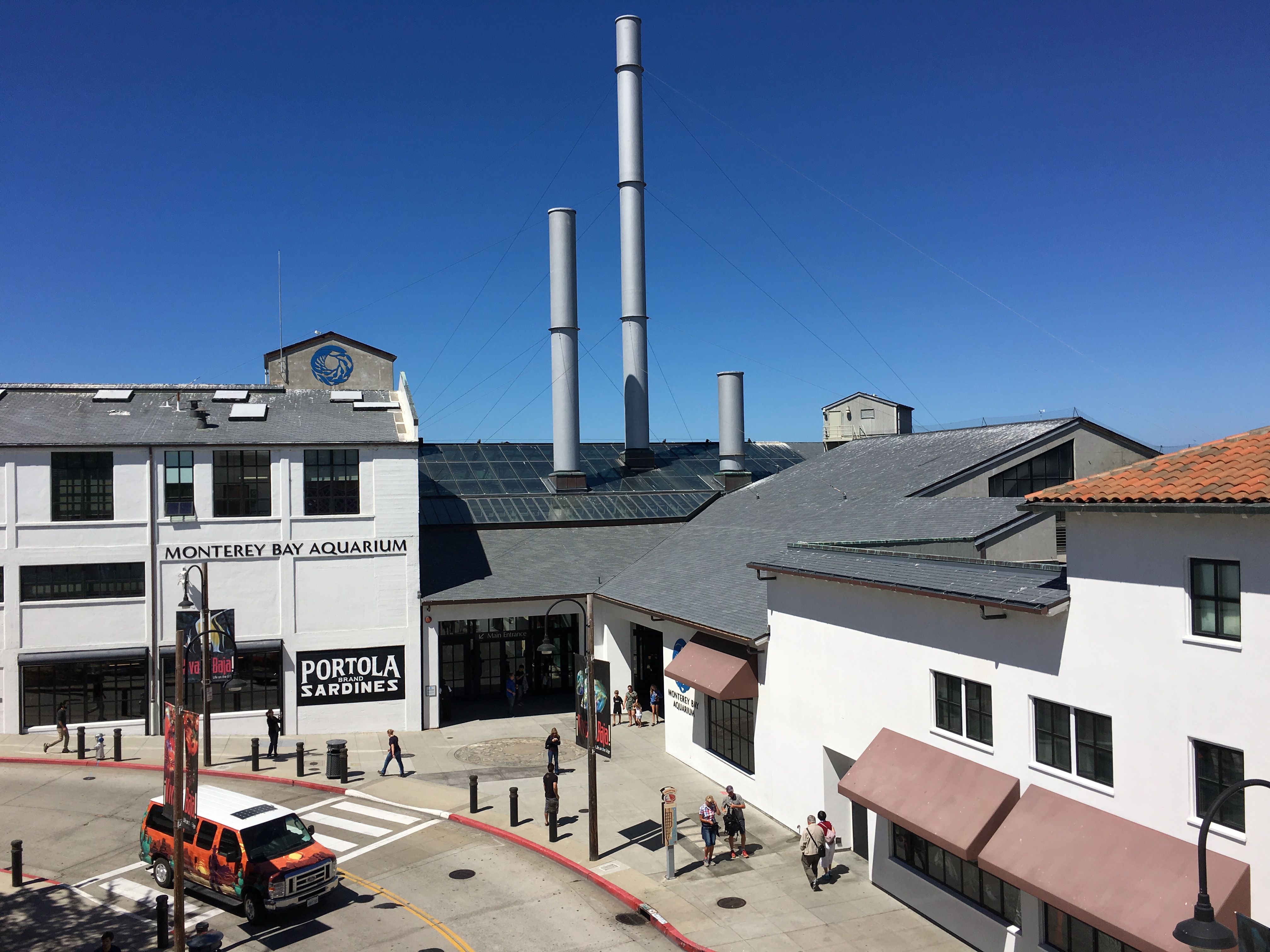 Exterior of the Monterey Bay Aquarium building on Cannery Row under a clear blue sky.