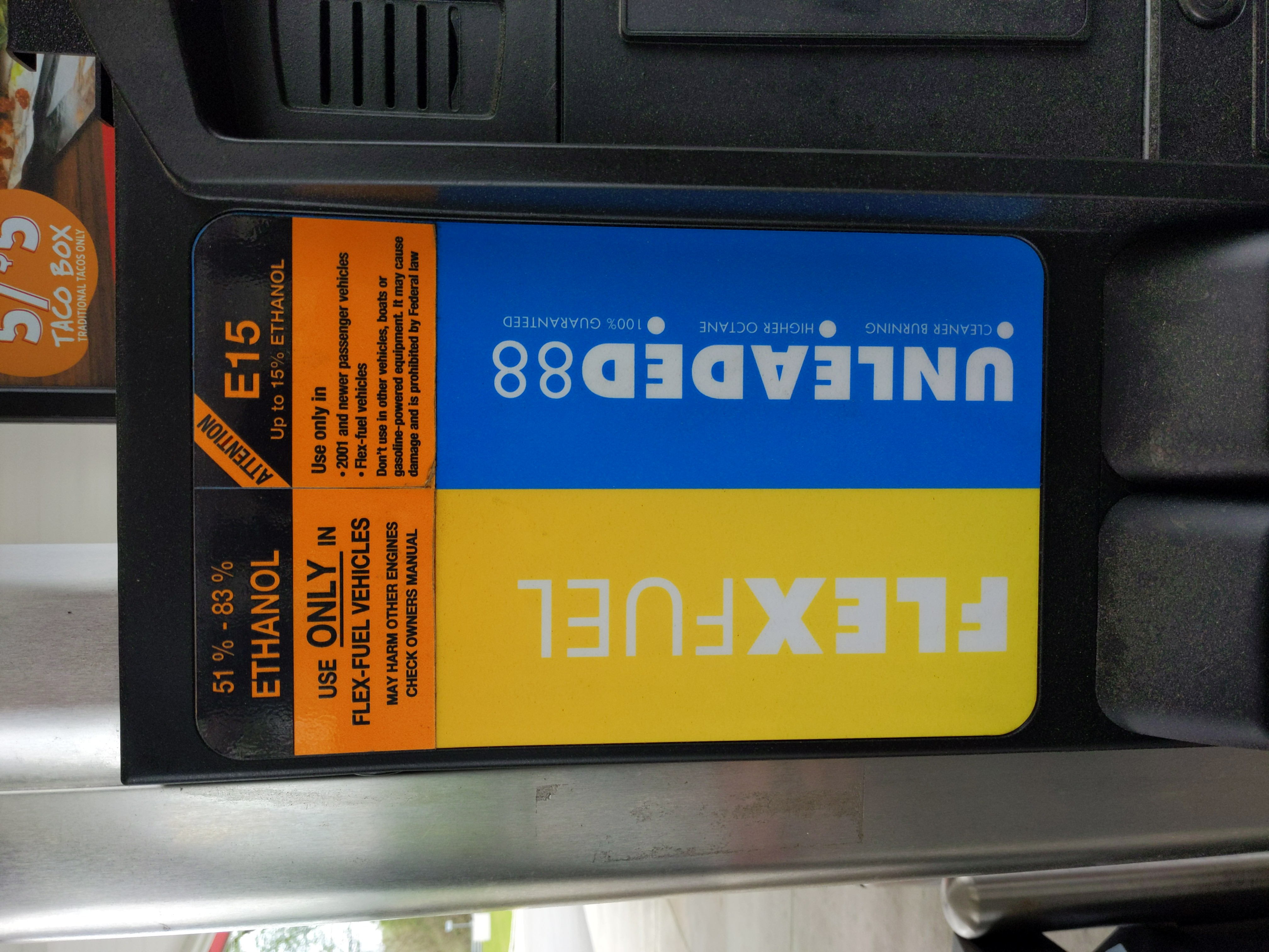 Orange and blue pump labels showing E15 ethanol fuel grade and vehicle compatibility warnings.