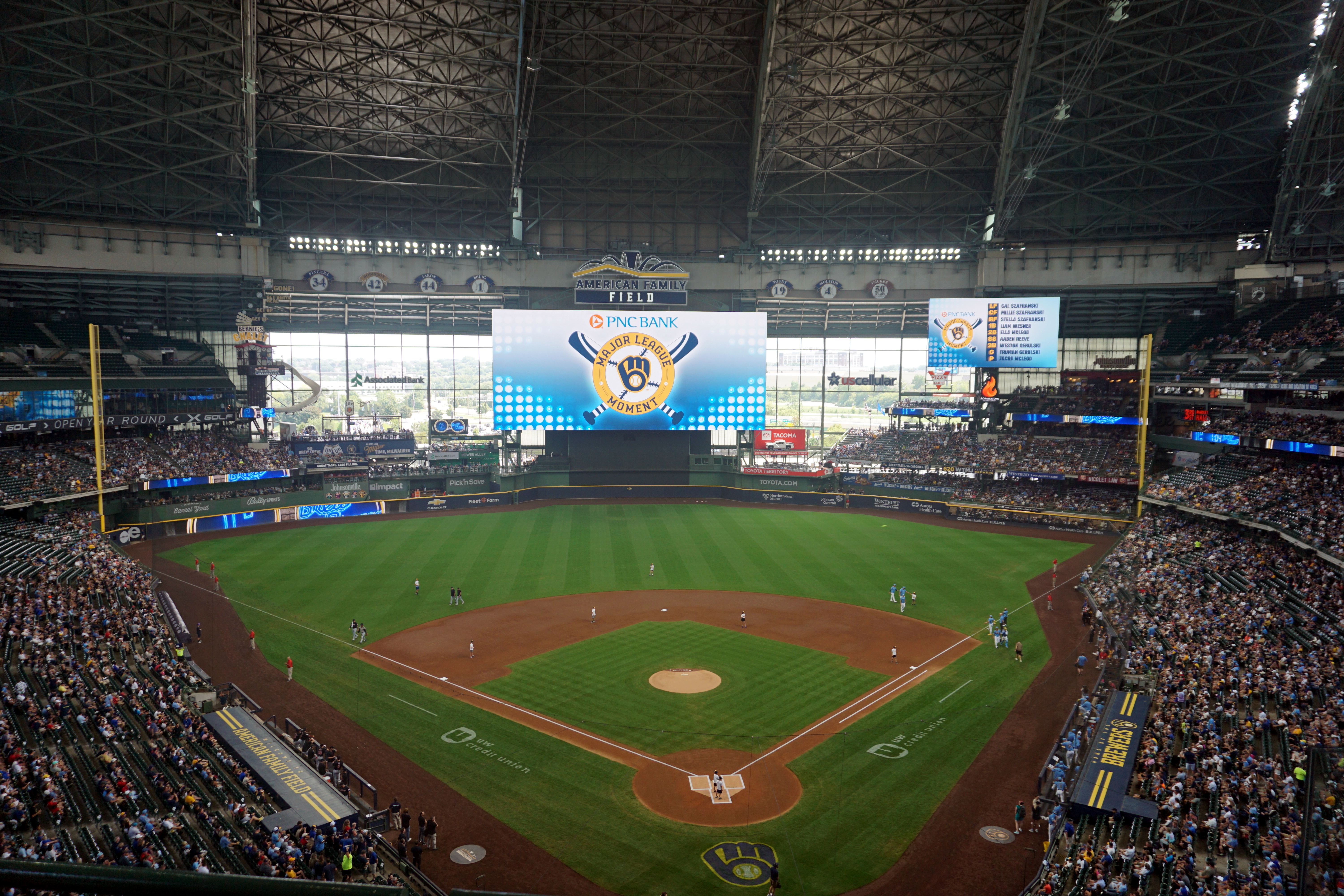 Interior of American Family Field with a packed crowd and the Brewers logo on the scoreboard.
