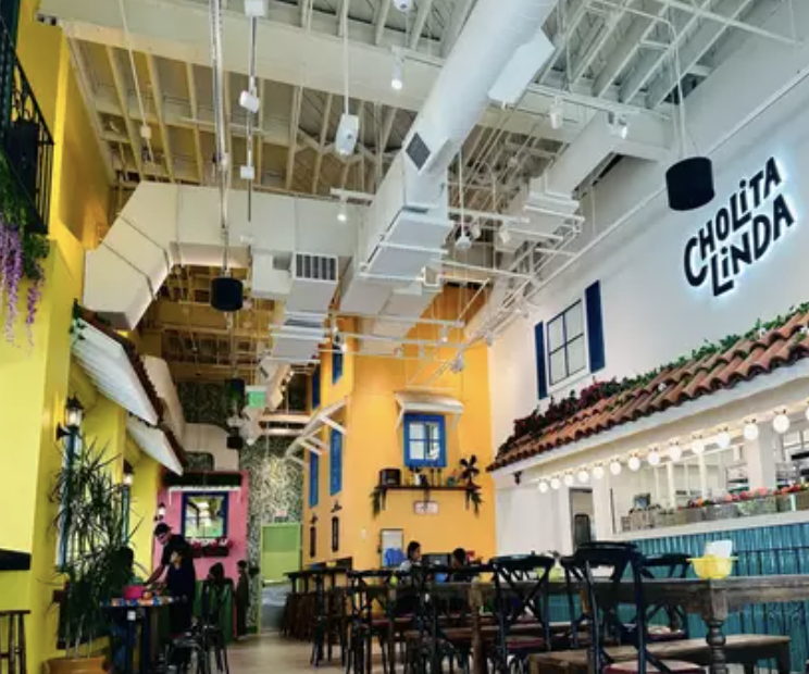 Colorful interior of a Cholita Linda restaurant with dining tables, bright walls and the restaurant logo.