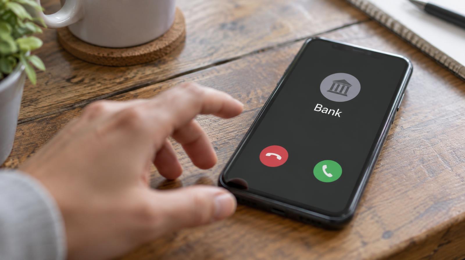 A smartphone on a wooden table showing an incoming call from a bank.