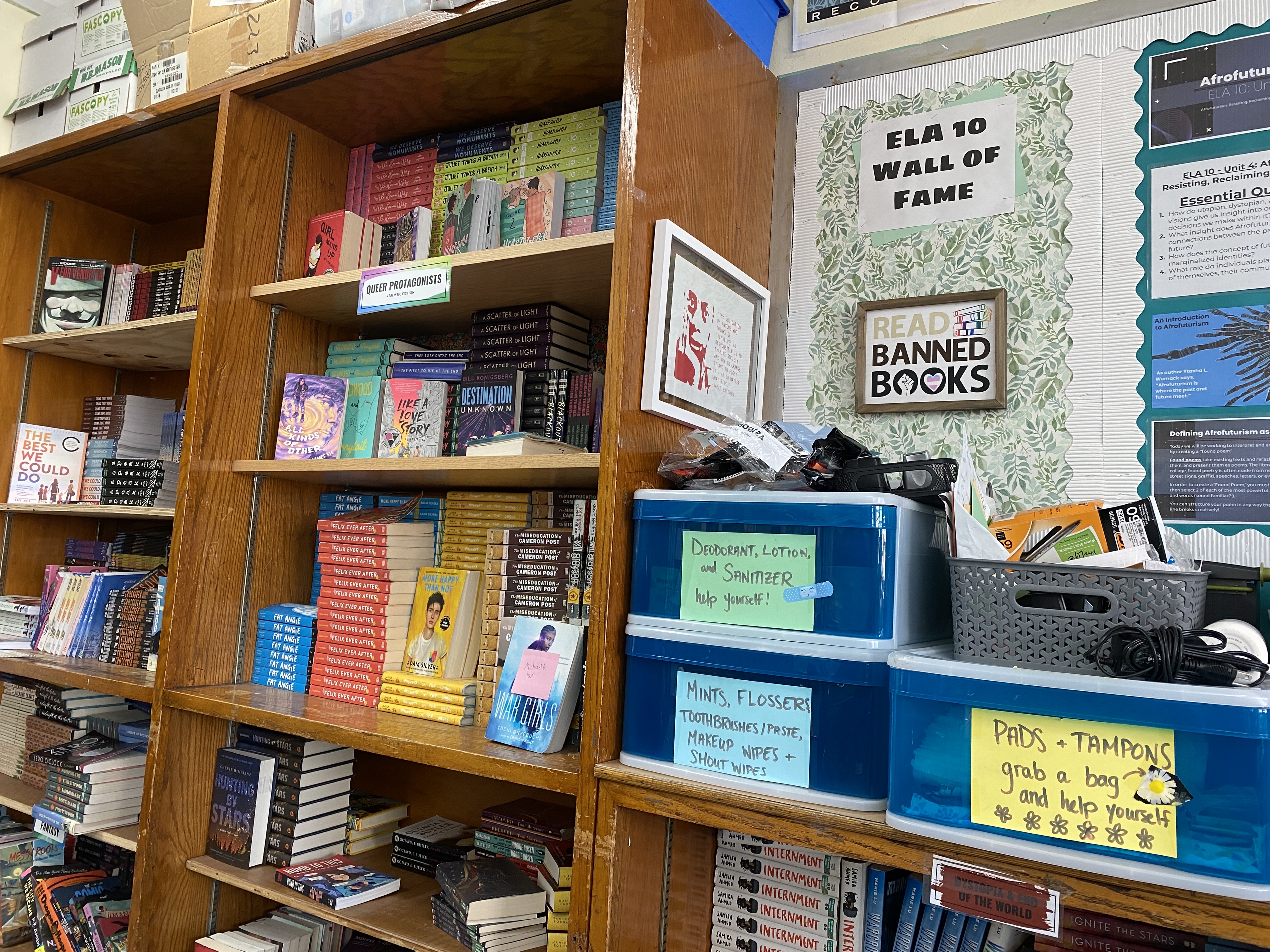 Classroom bookshelves filled with colorful books beside a bulletin board in a school library.