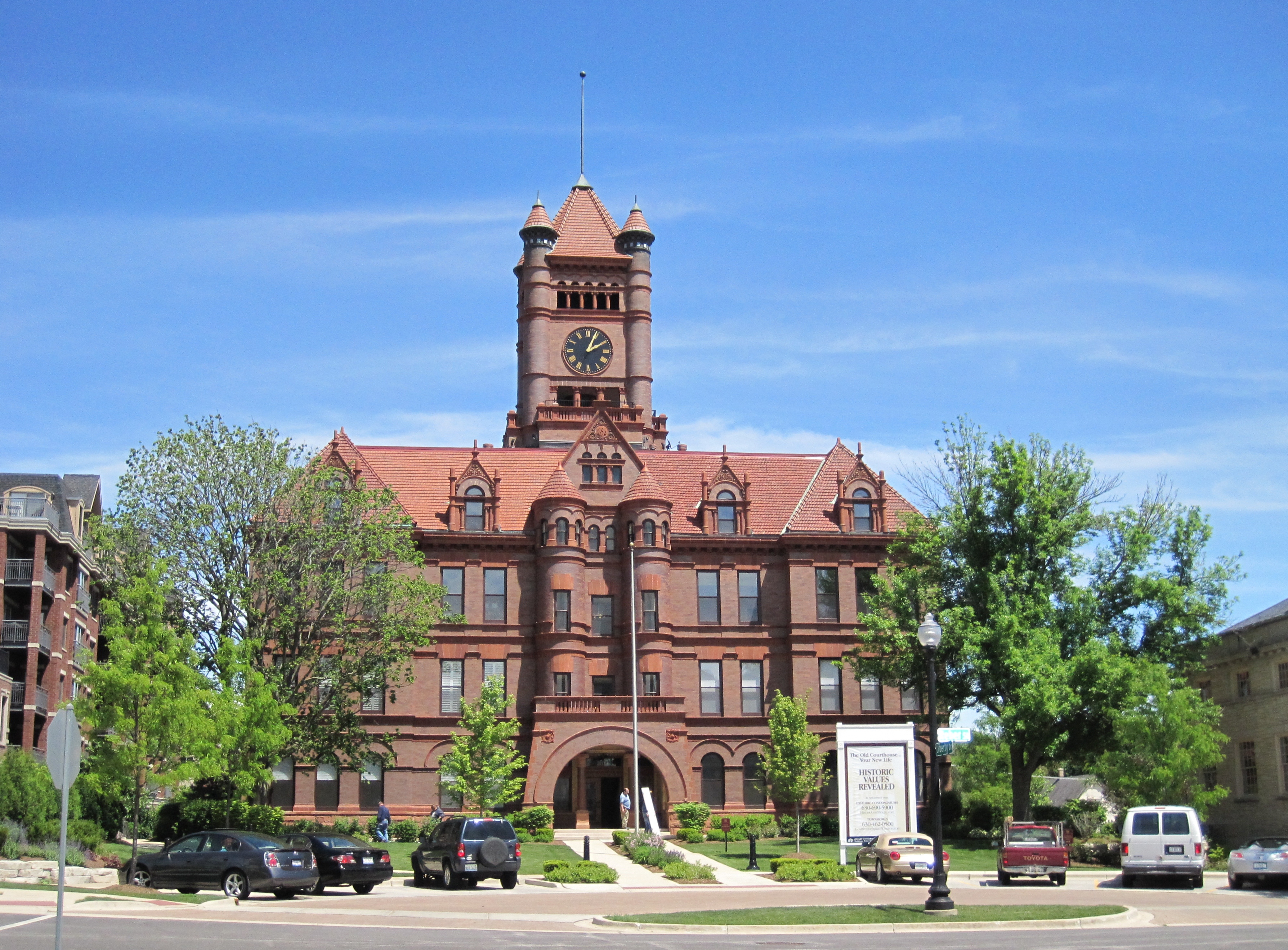 Red-brick Victorian courthouse with a tall clock tower, surrounded by trees.
