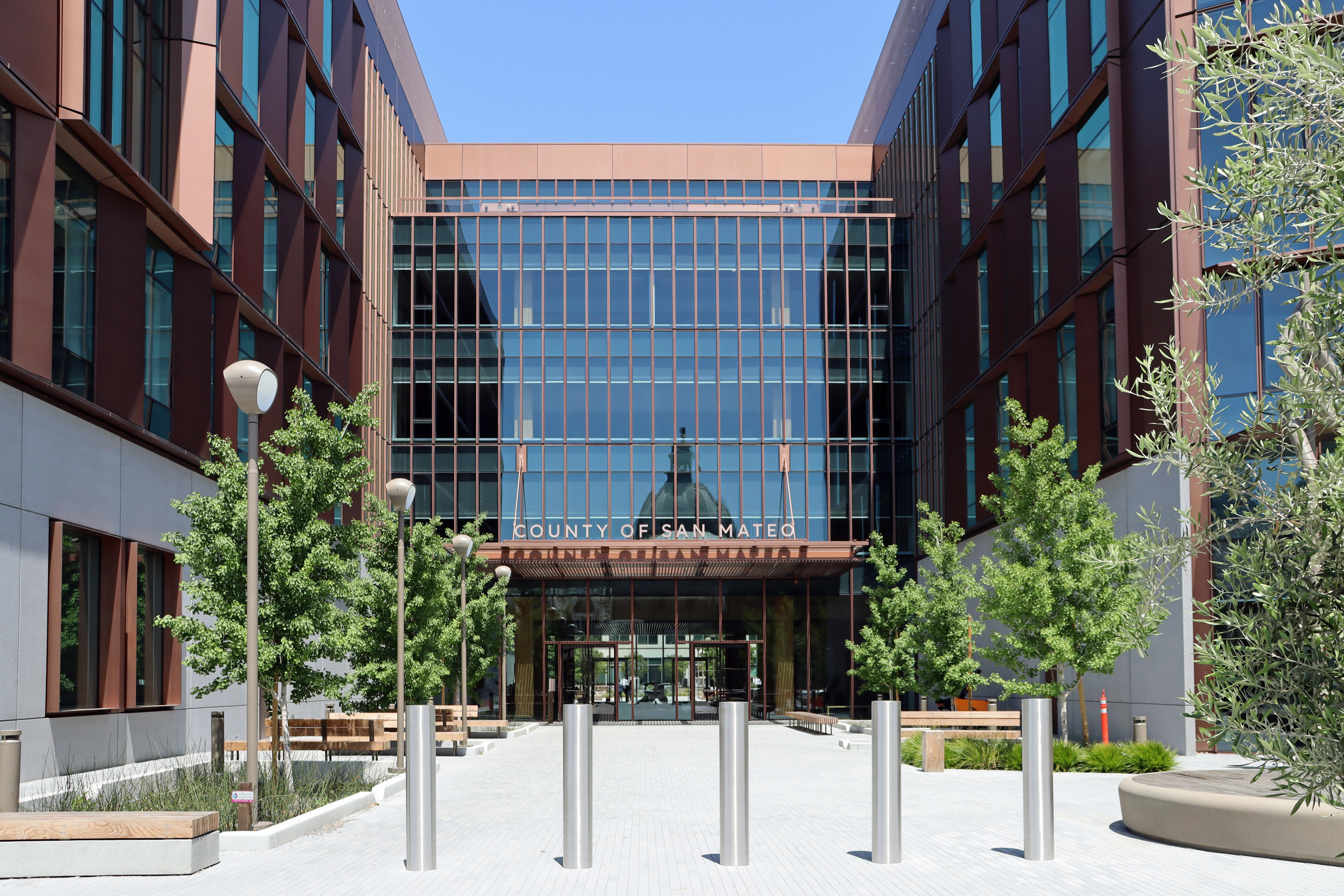 Multi-story government office building with glass facade and brick exterior at a plaza entrance.