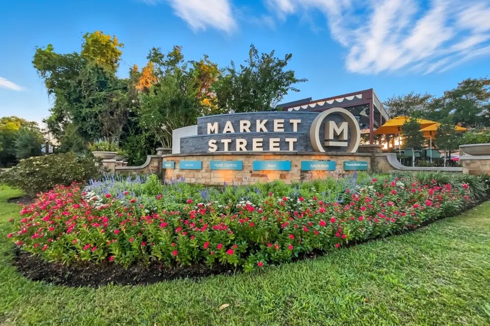 Monument sign reading 'Market Street' surrounded by colorful flower beds and trees.