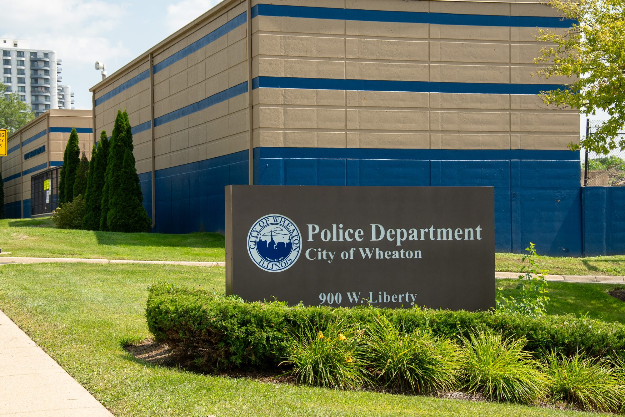 Monument sign for the City of Wheaton Police Department outside a tan and blue building.