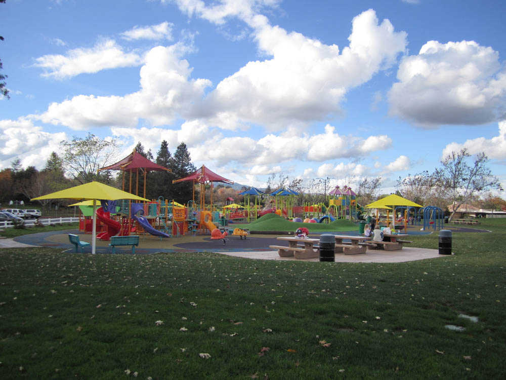 Colorful all-abilities playground with shade canopies, slides, and accessible rubber pathways.