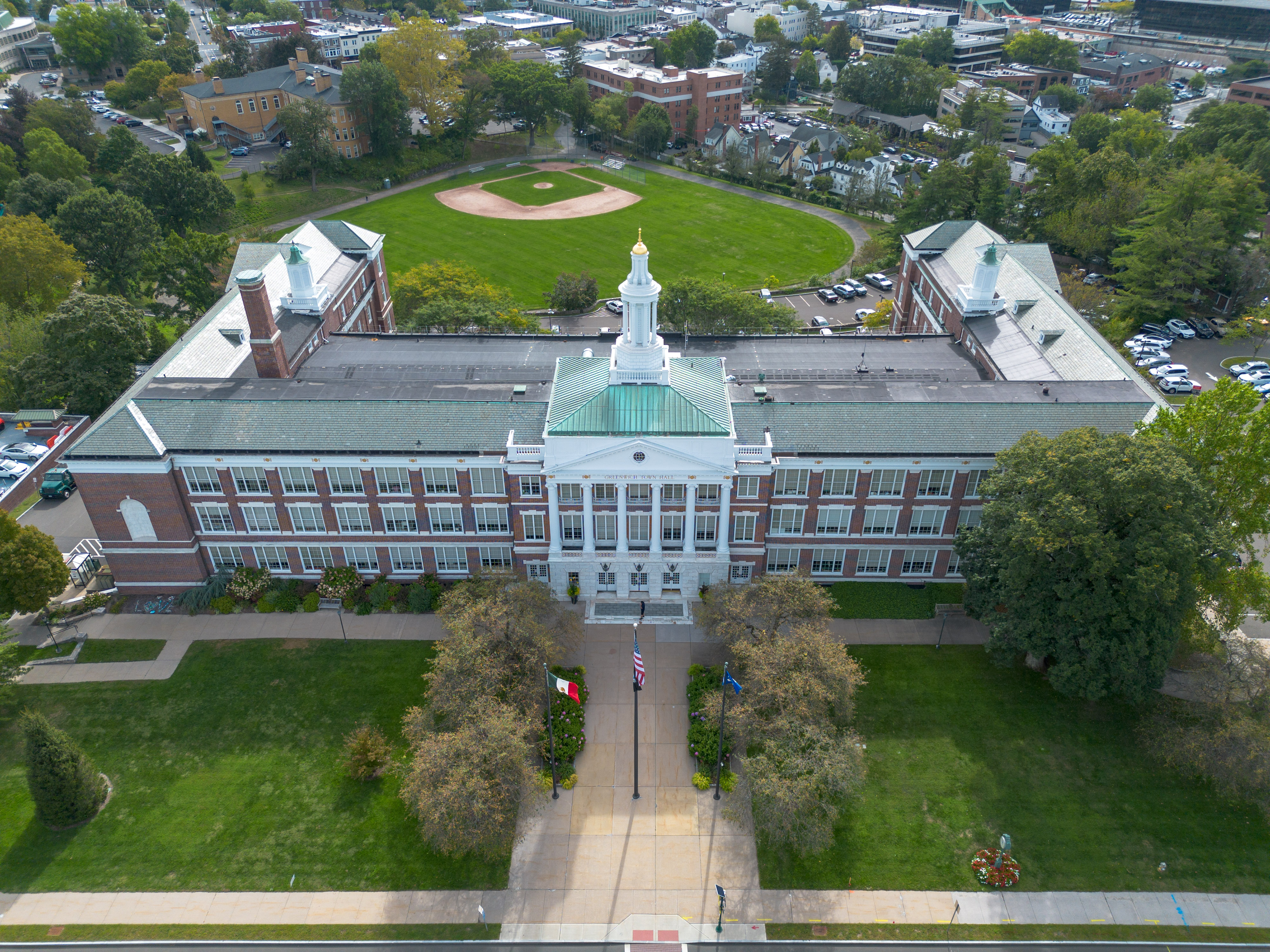 Aerial view of Greenwich Town Hall, a brick building with a white cupola and green copper roof.