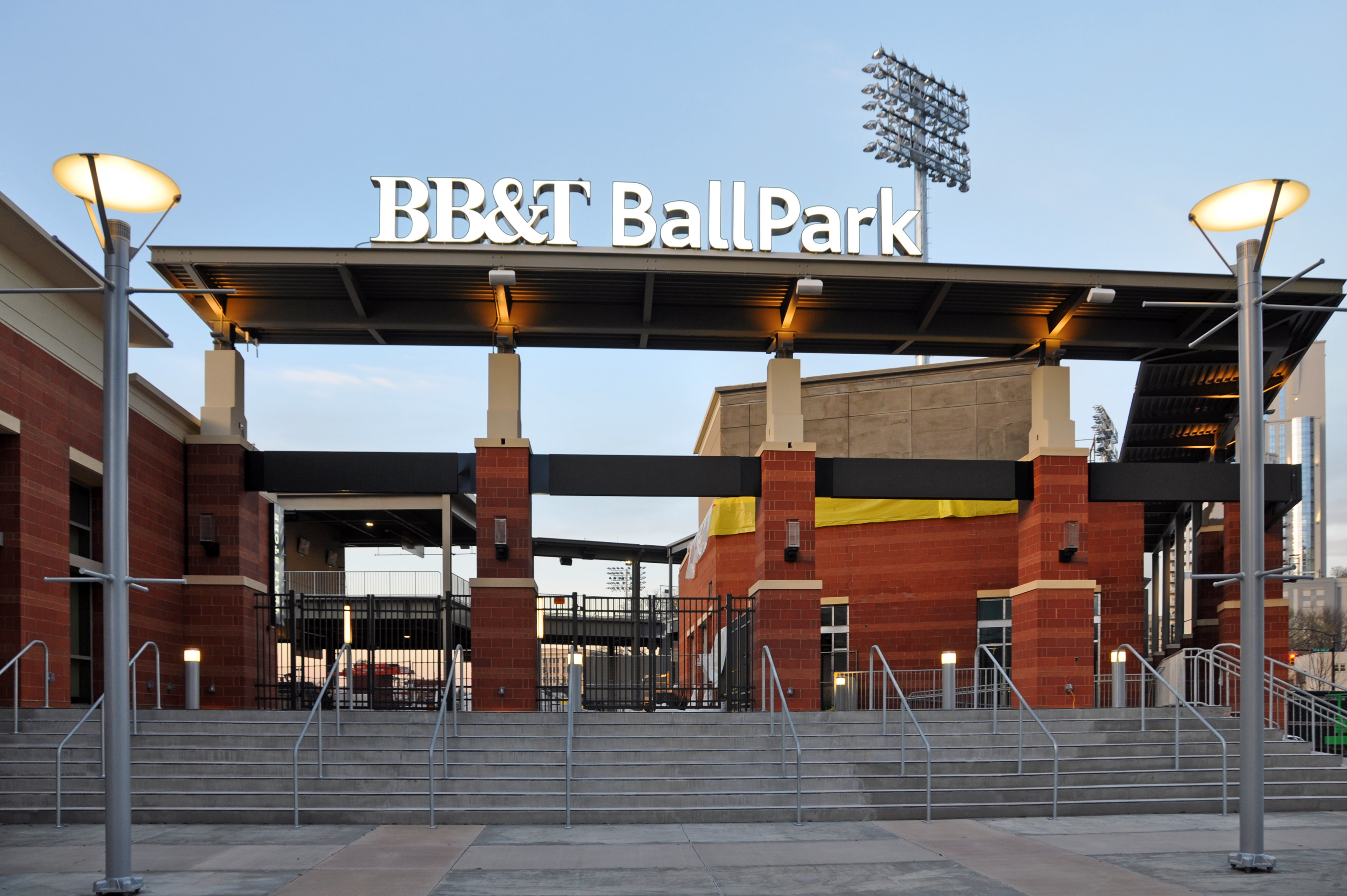 Illuminated entrance sign and brick facade of a baseball stadium at dusk.