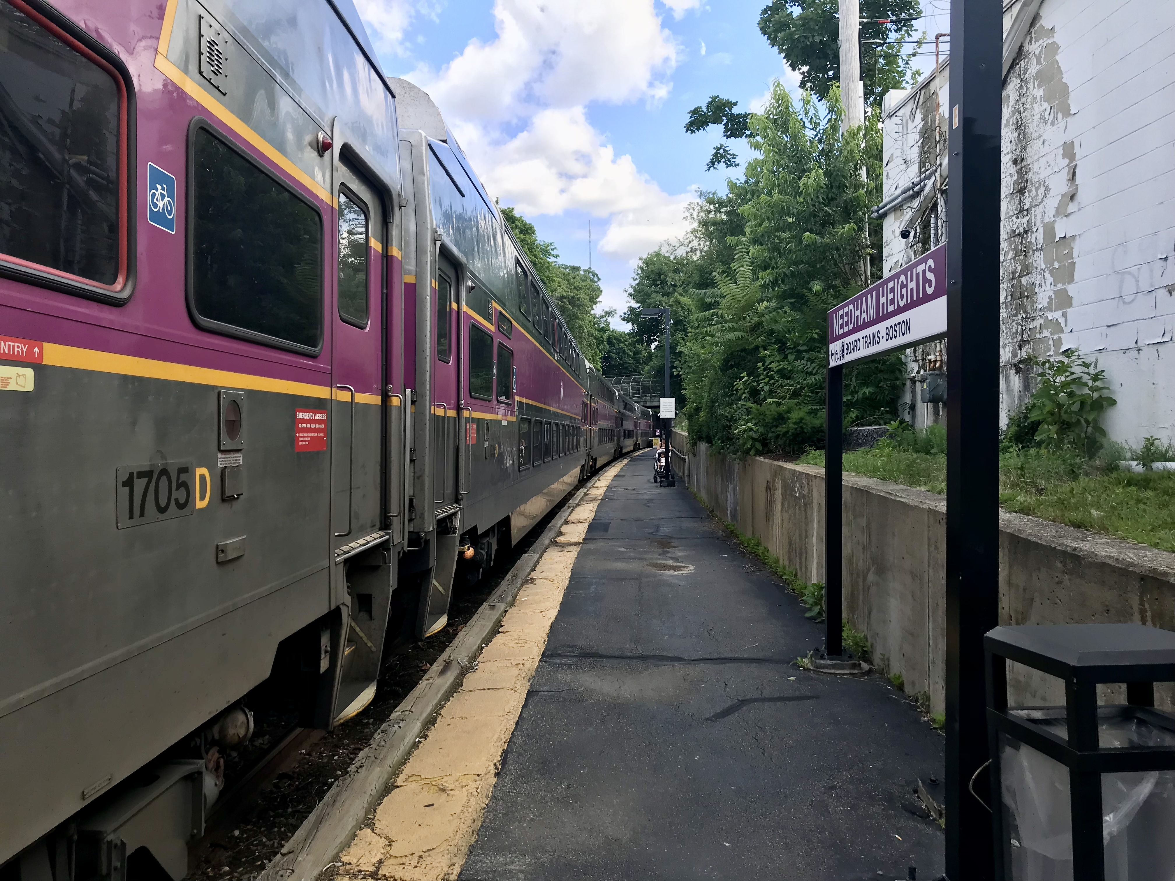 MBTA commuter rail train stopped at a platform with a Needham Heights station sign visible.