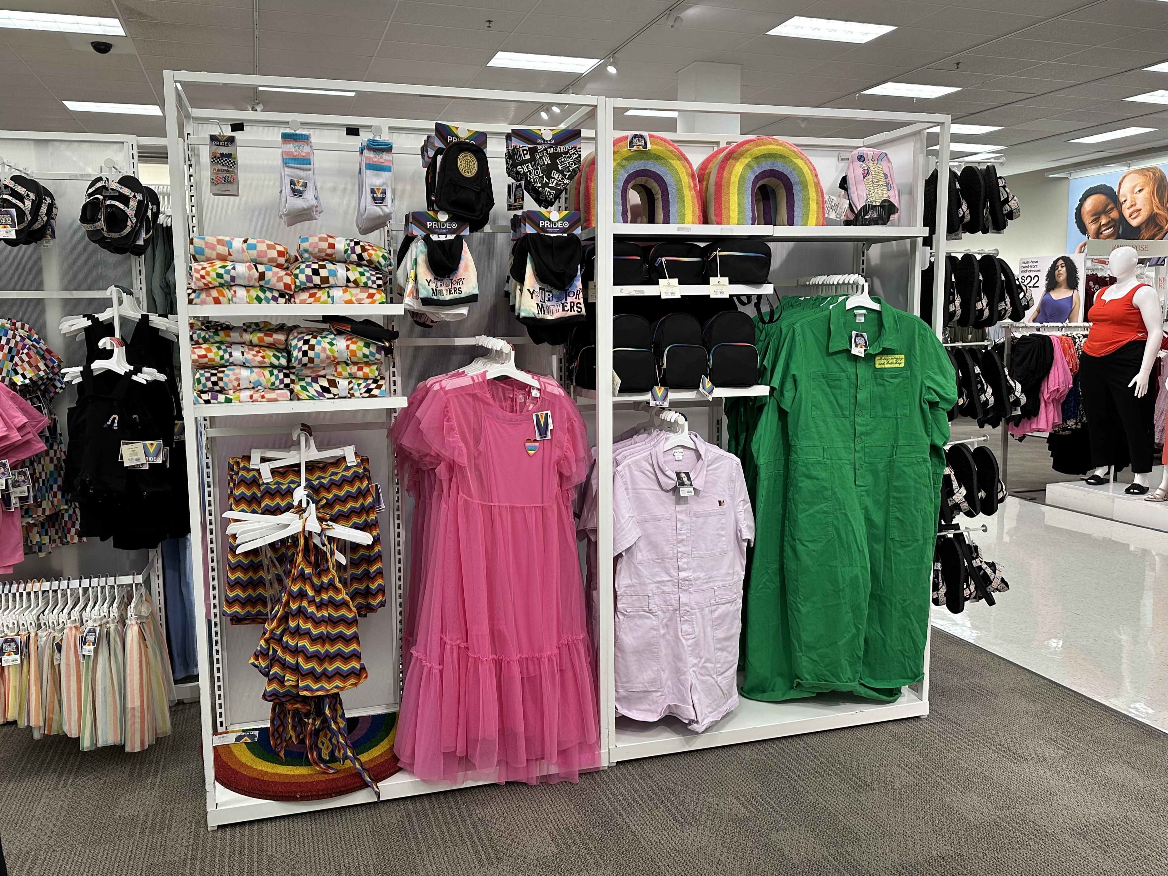 Children's clothing items displayed on white shelving units inside a retail store.
