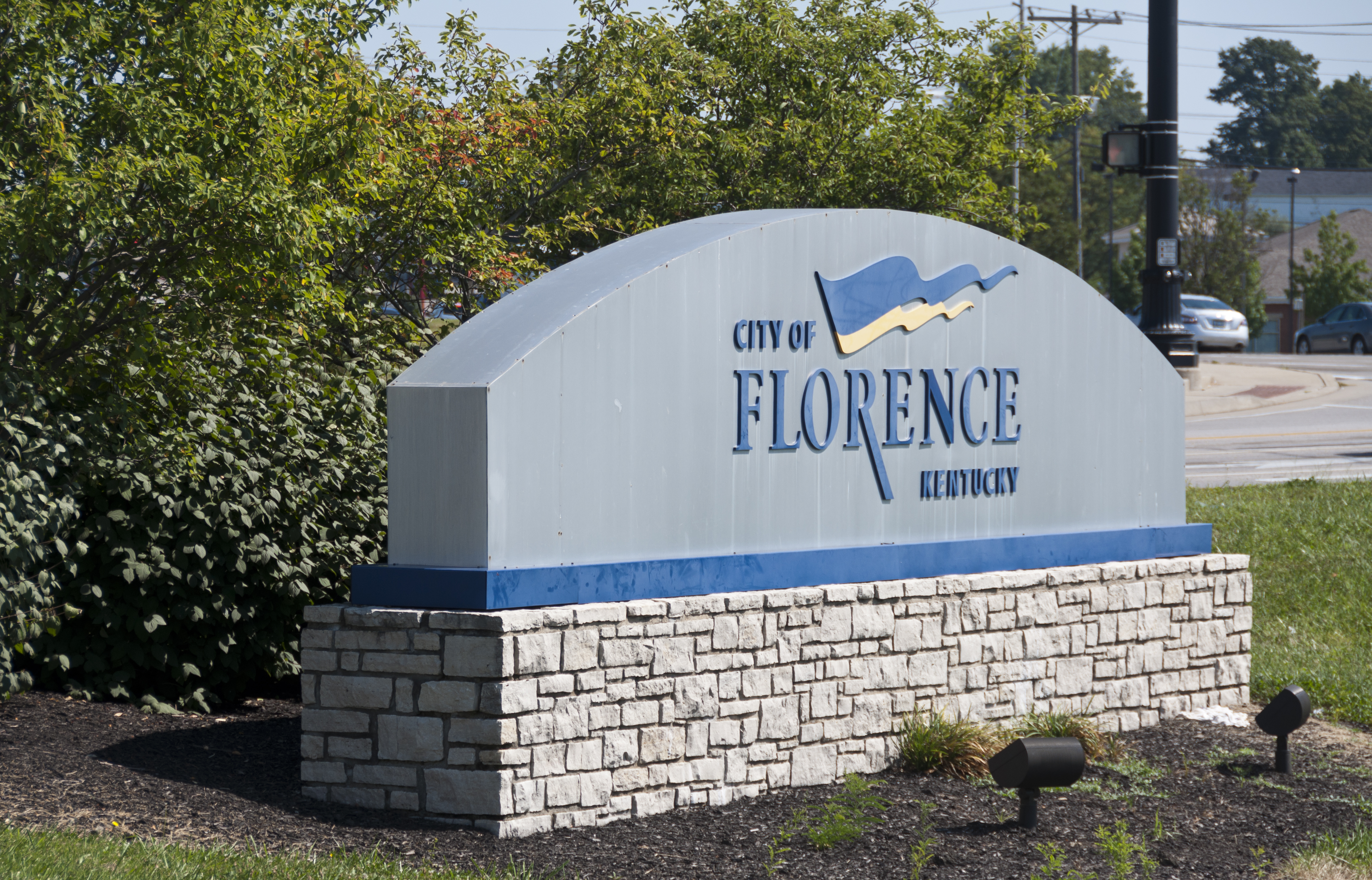 Stone monument sign reading 'City of Florence Kentucky' near a road intersection.