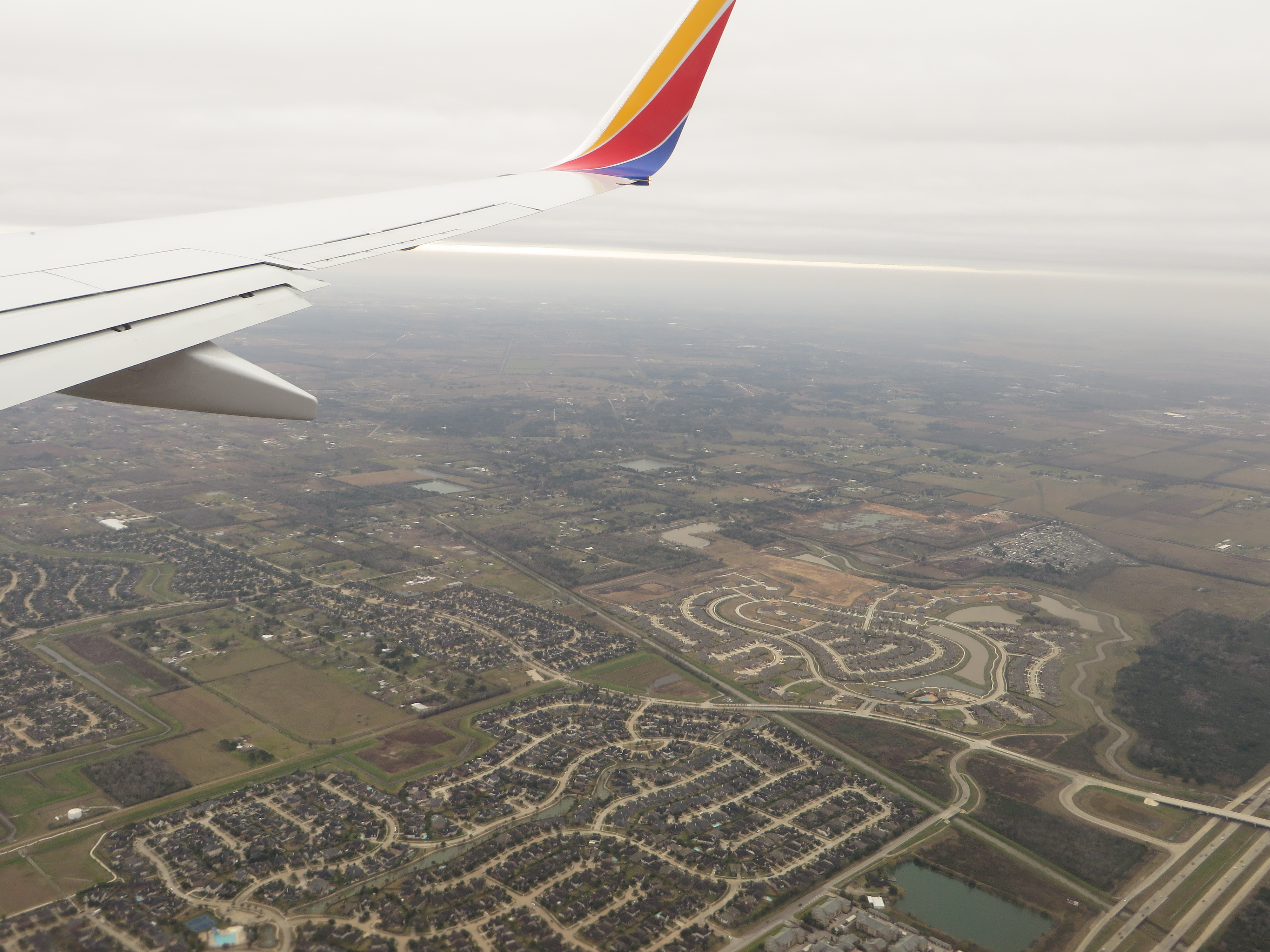 Aerial view of suburban subdivisions with winding streets and open undeveloped land.
