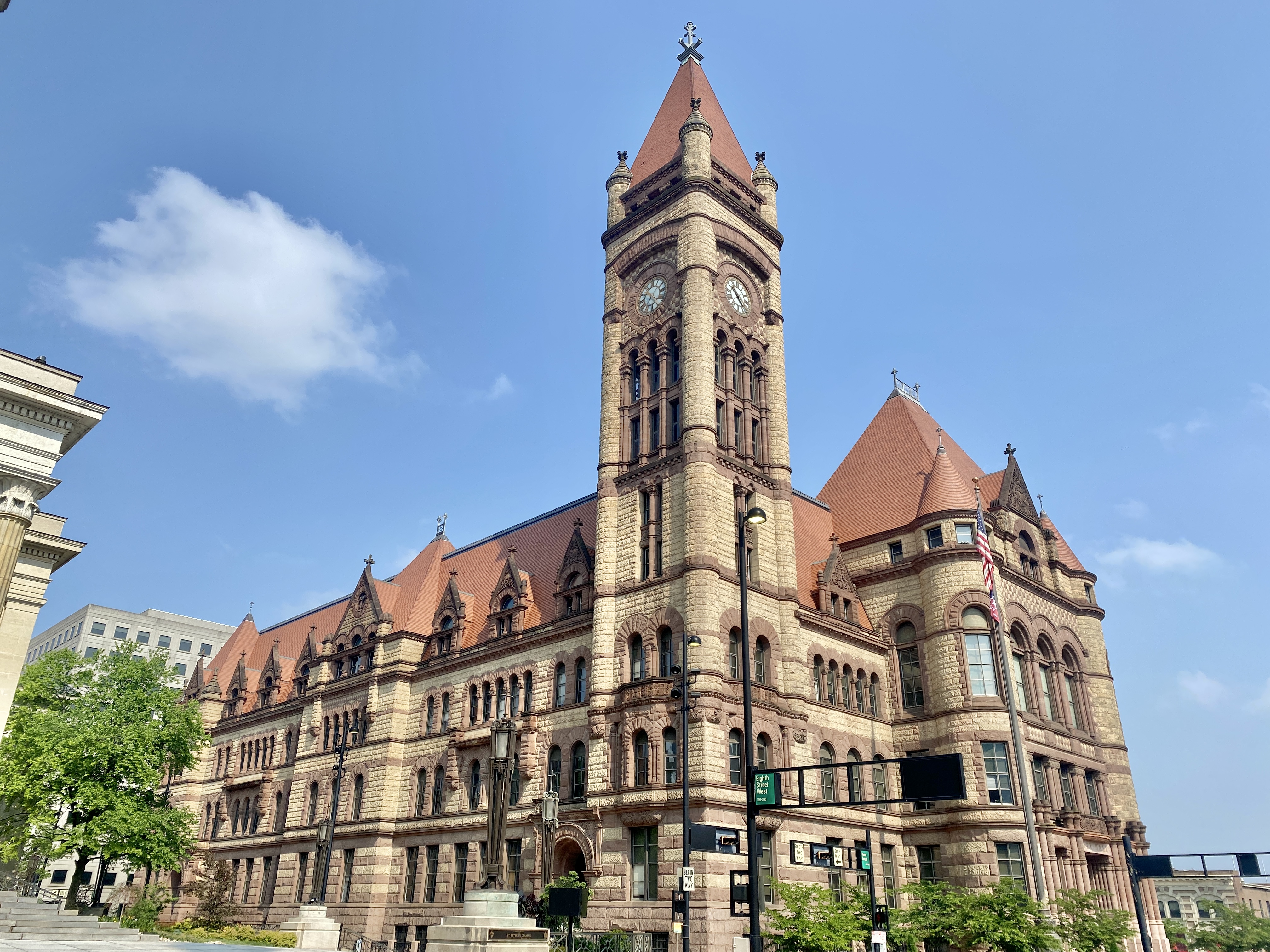 Large stone government building with a tall clock tower under blue sky.