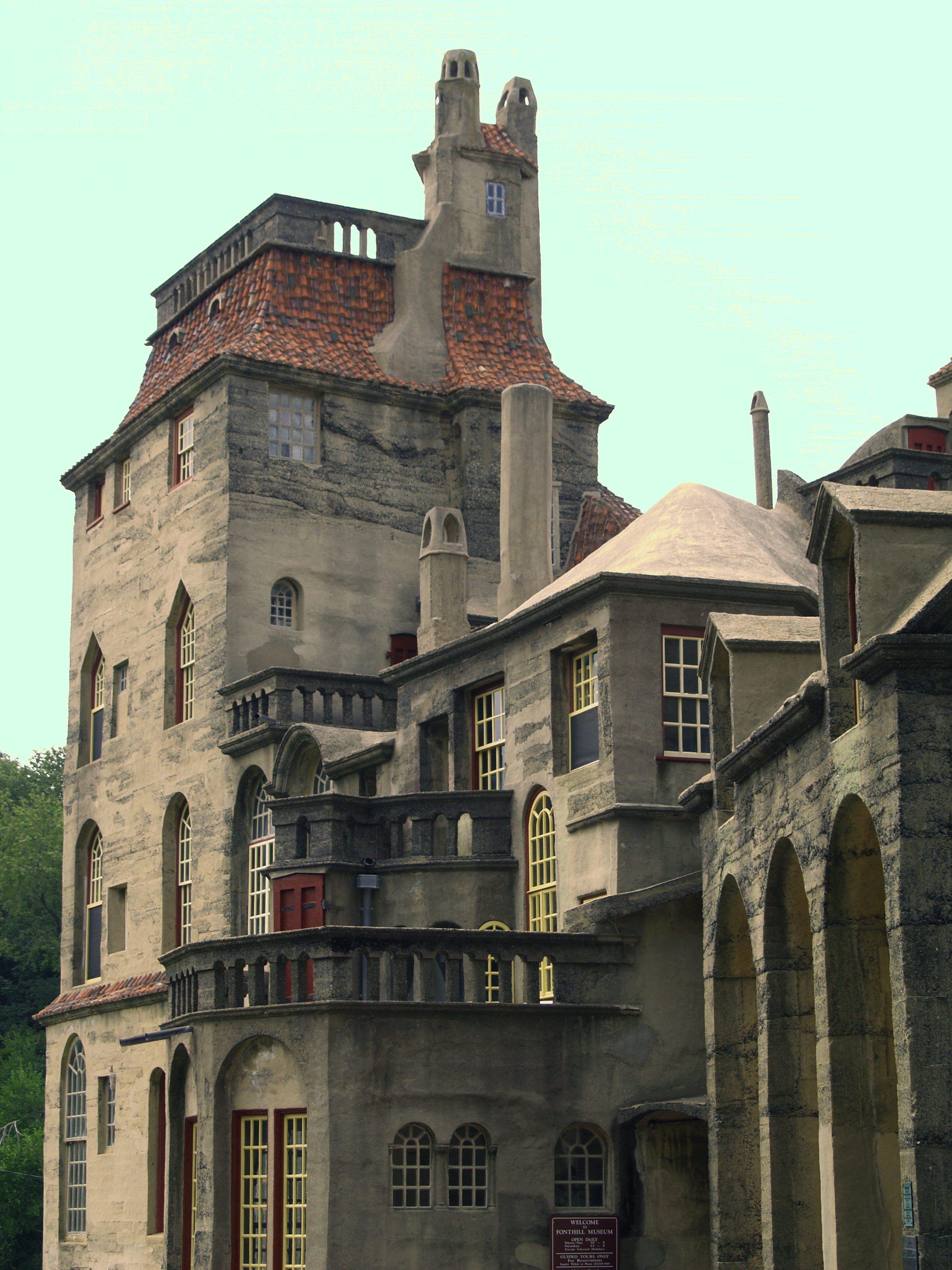 Stone castle tower with terracotta tile roof, arched windows, and a decorative balcony