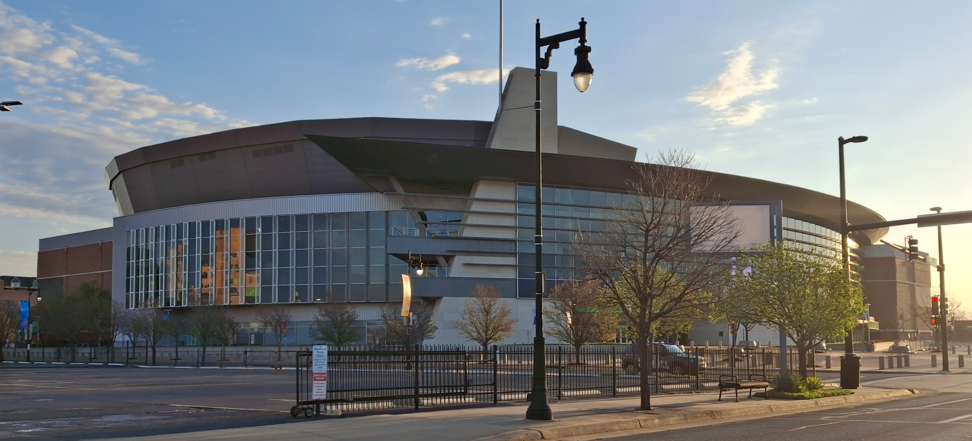Exterior corner of a large arena building with curved roof and glass facade.