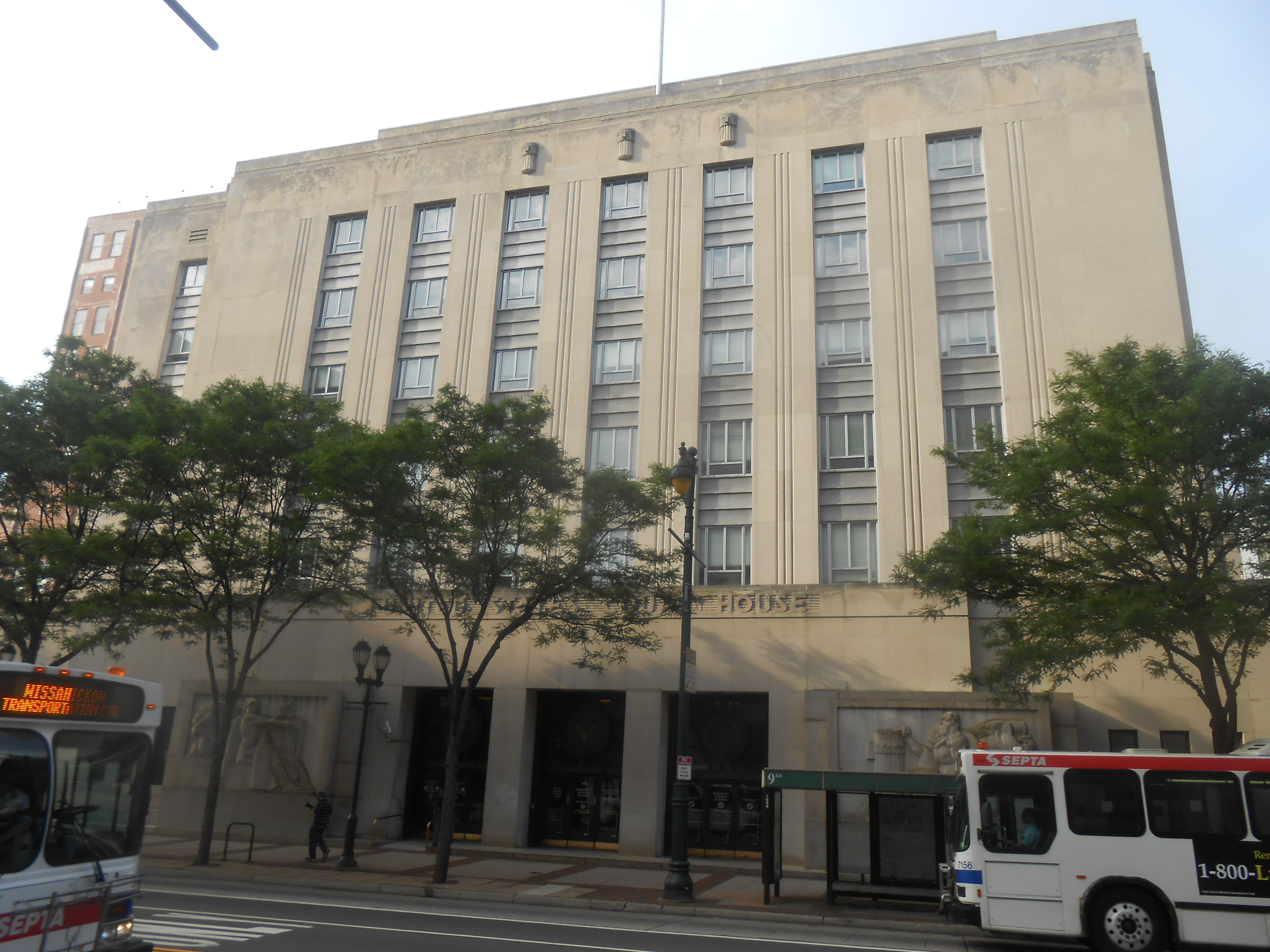 Art Deco federal courthouse building on a Philadelphia street lined with trees.