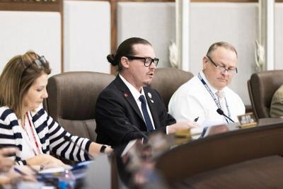 Three people seated at a curved government council dais during a meeting.